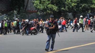 A man is seen holding a gun as people run away in central Jakarta, Indonesia [Reuters]