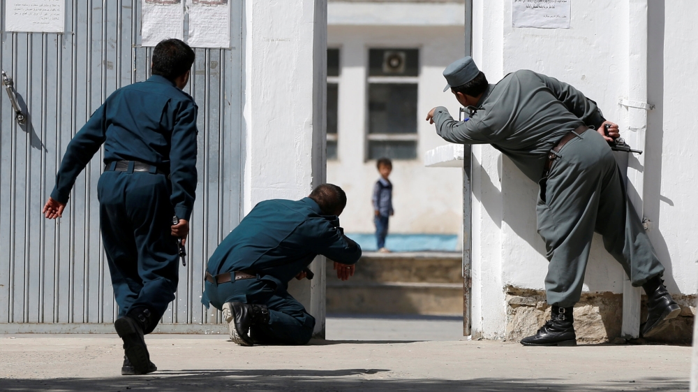 Afghan policemen try to rescue a child at the site of athe suicide attack [Omar Sobhani/Reuters]