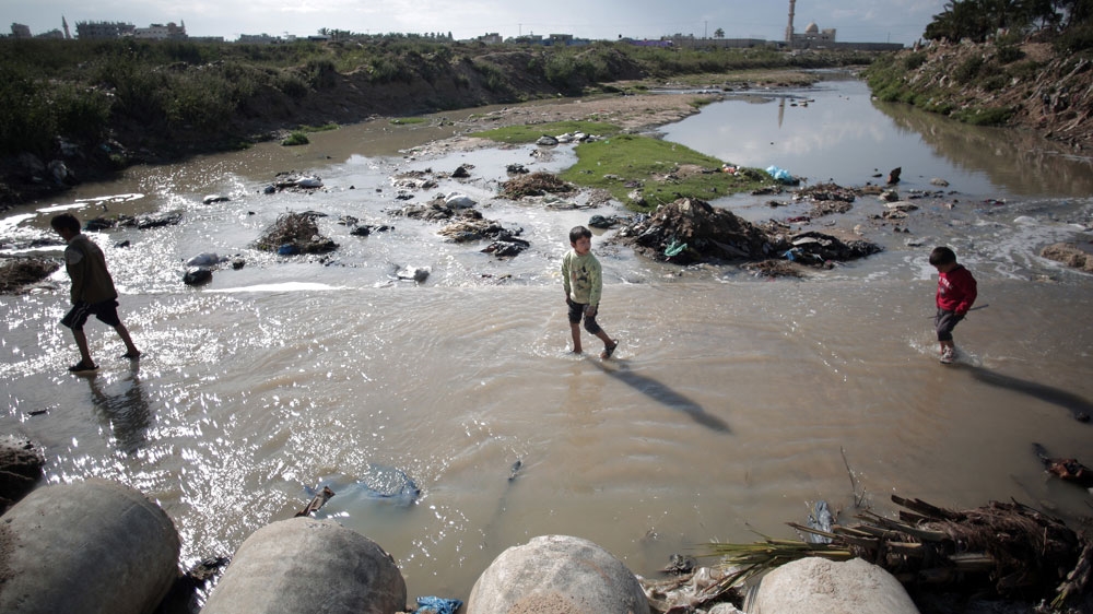 Children make their way through sewage water in Mighraqa neighbourhood on the outskirts of Gaza City [File: Khalil Hamra/AP Photo]