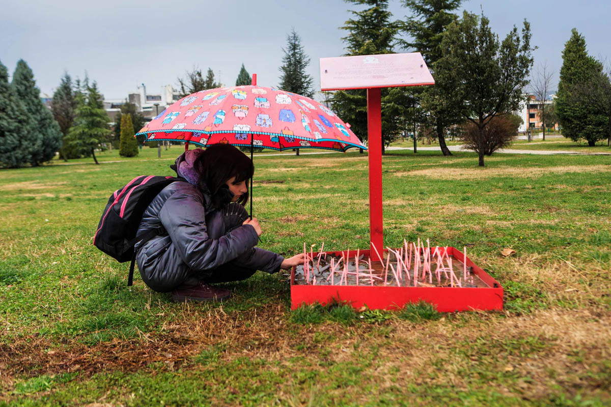 A little girl lights a candle at the memorial for girls who were never born at the university park in Podgorica.