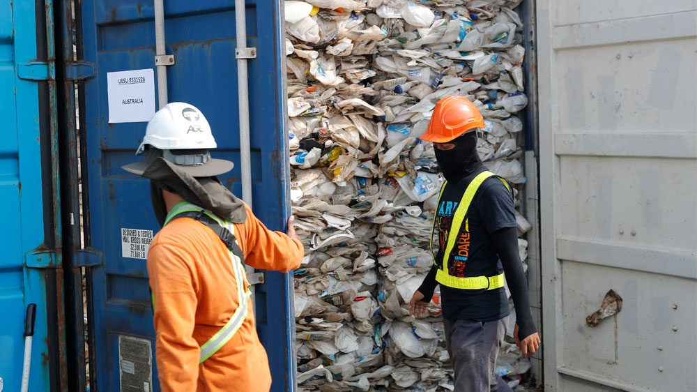 Workers open a container full of non-recyclable plastic seized by authorities at the west port in Klang, Malaysia