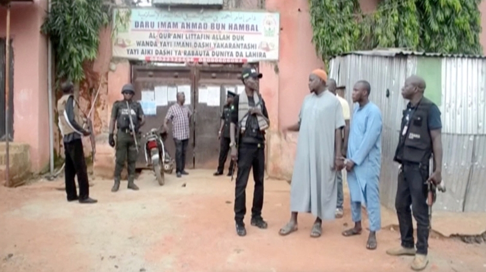 Police officers stand with detained islamic teachers in the northern city of Kaduna