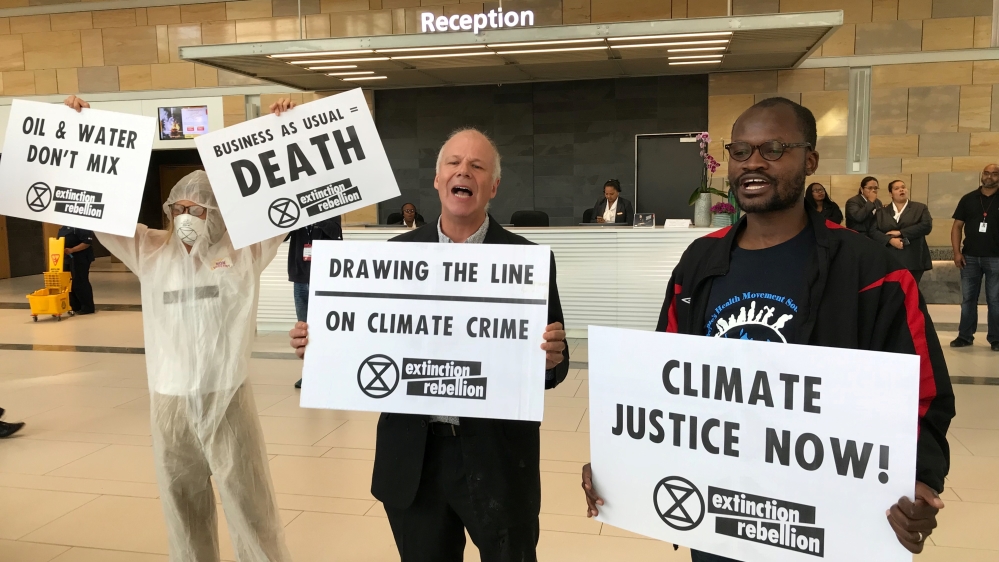 Protestors from climate change awareness collective Extinction Rebellion smear oil across the floor at the lobby of the Africa Oil Week conference in Cape Town