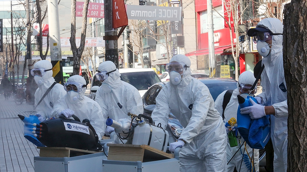 Workers wearing protective gears spray disinfectant as a precaution against the coronavirus at a shopping street in Seoul, South Korea, Thursday, Feb. 27, 2020. The new illness persists in the worst-h