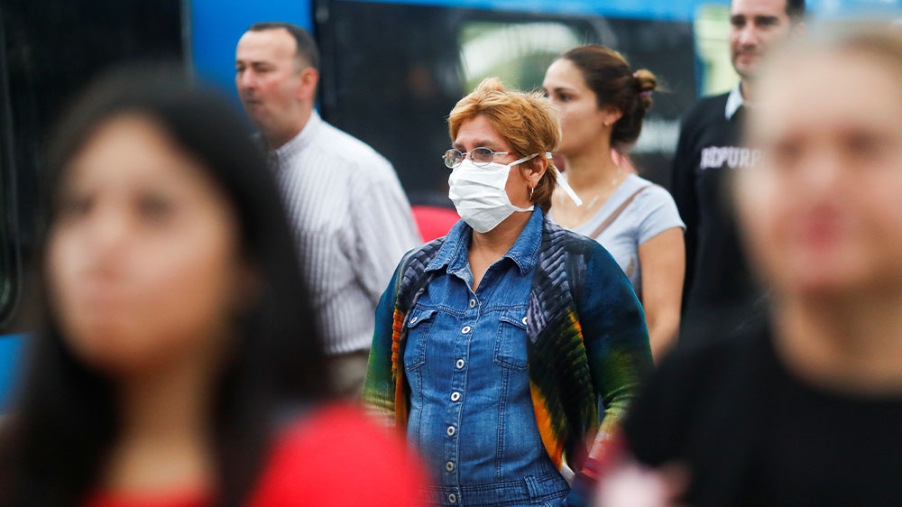 A woman wearing a protective face mask while walking near the Constitution train station, in Buenos Aires, Argentina