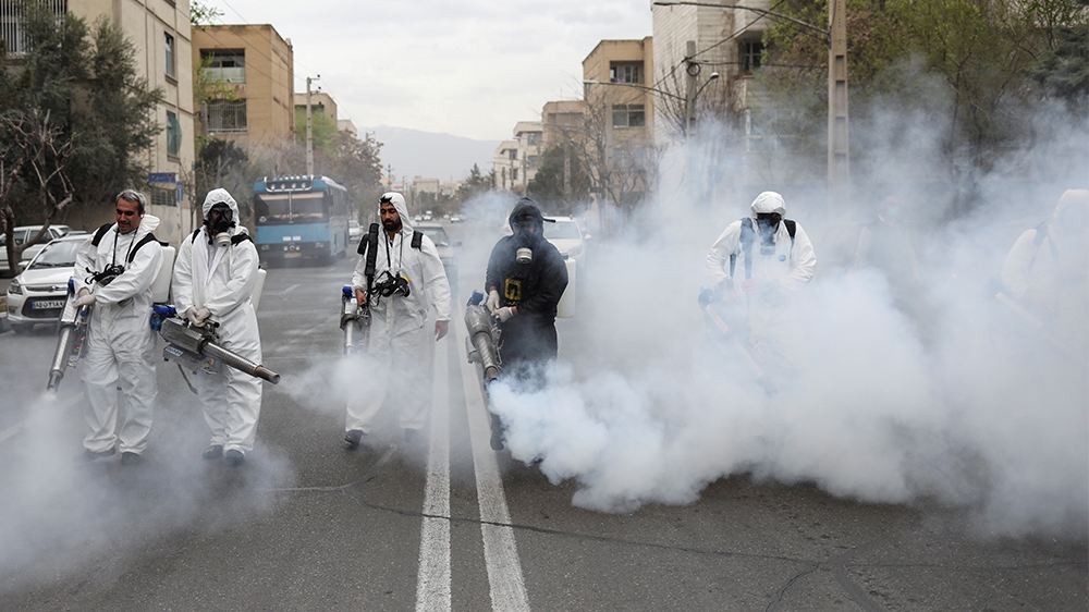 Members of firefighters wear protective face masks, amid fear of coronavirus disease (COVID-19), as they disinfect the streets, ahead of the Iranian New Year Nowruz, March 20, in Tehran, Iran March 18