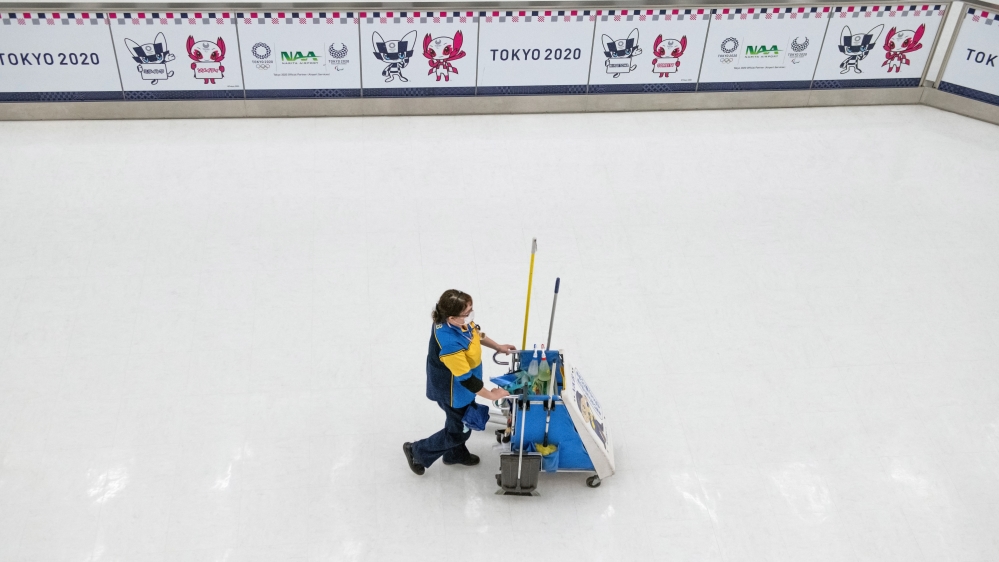 A cleaner pushes a cart past Tokyo 2020 Olympics adverts at Narita Airport amid lockdown