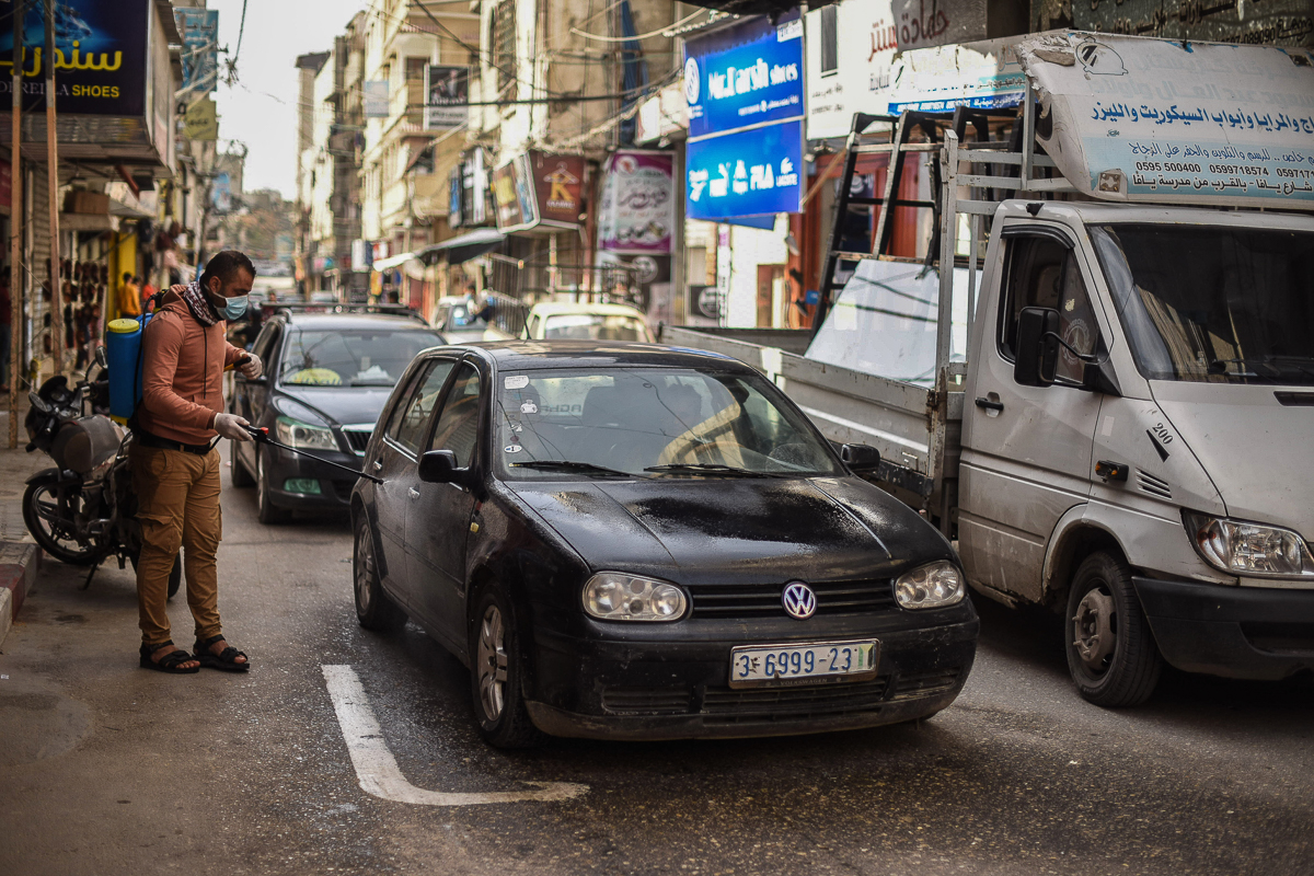 A young Palestinian man volunteers to disinfect streets and cars in Khan Yunis.