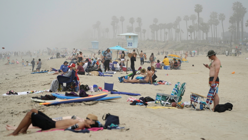 People sit in groups at Huntington City Beach during the outbreak of the coronavirus disease in Huntington Beach, California, US