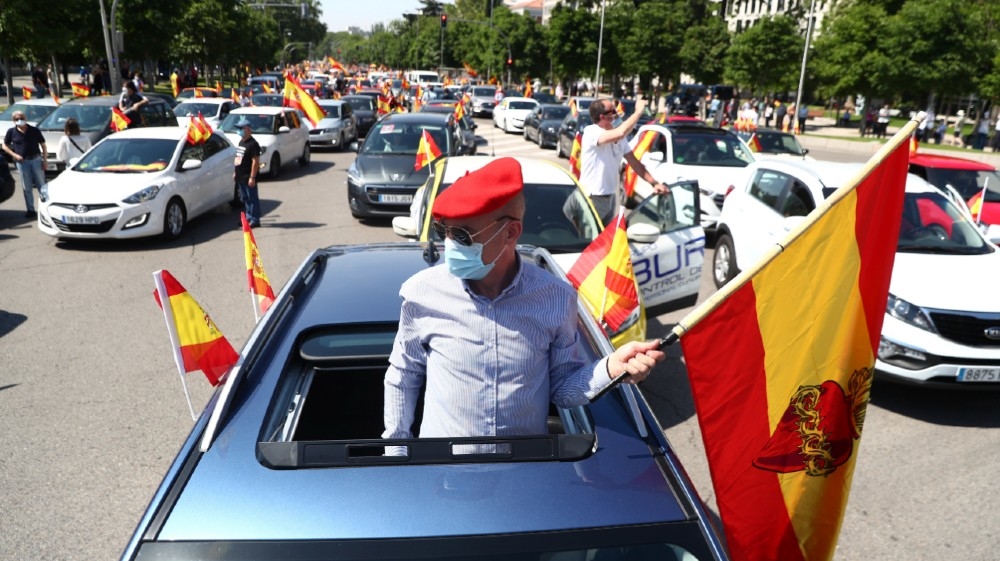 A demonstrator wearing a protective face mask carries a flag during a protest organised by Spain’s far-right party Vox against the government’s handling of the coronavirus pandemic in Madrid, Spain