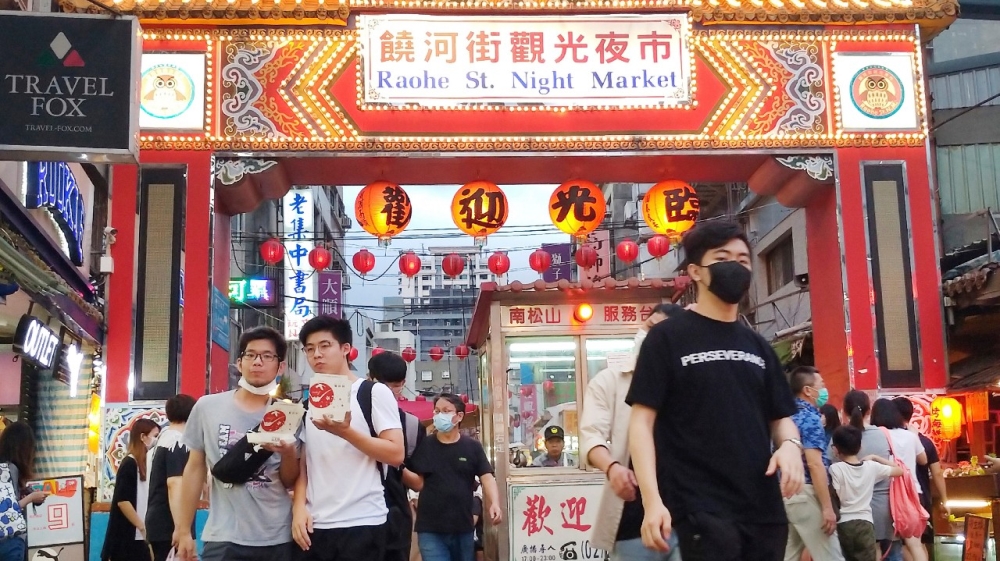 People wear face masks to help curb the spread of the coronavirus as they visit a night market in Taipei, Taiwan