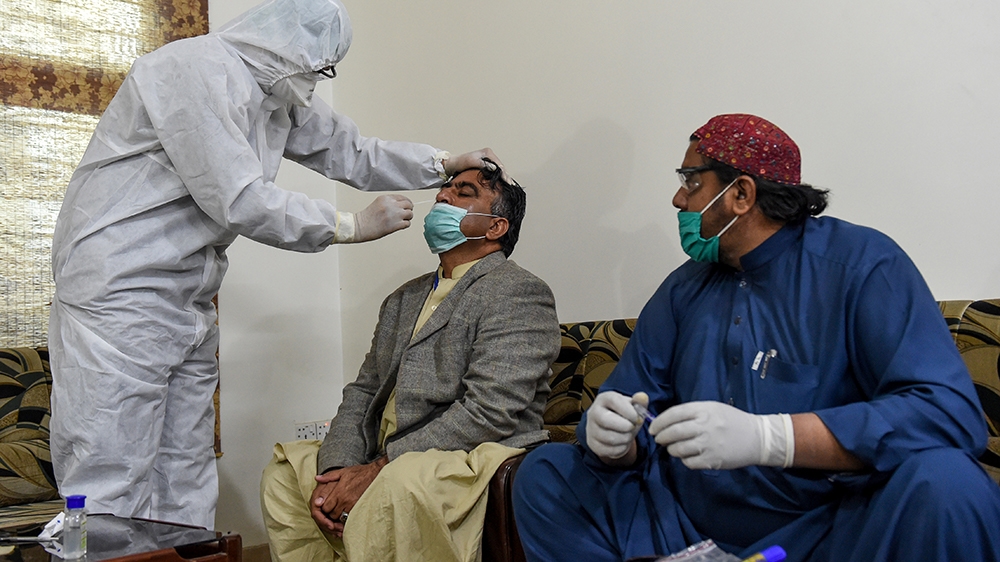 A healthcare worker takes a testing sample from a journalist during a government-imposed nationwide lockdown in Quetta