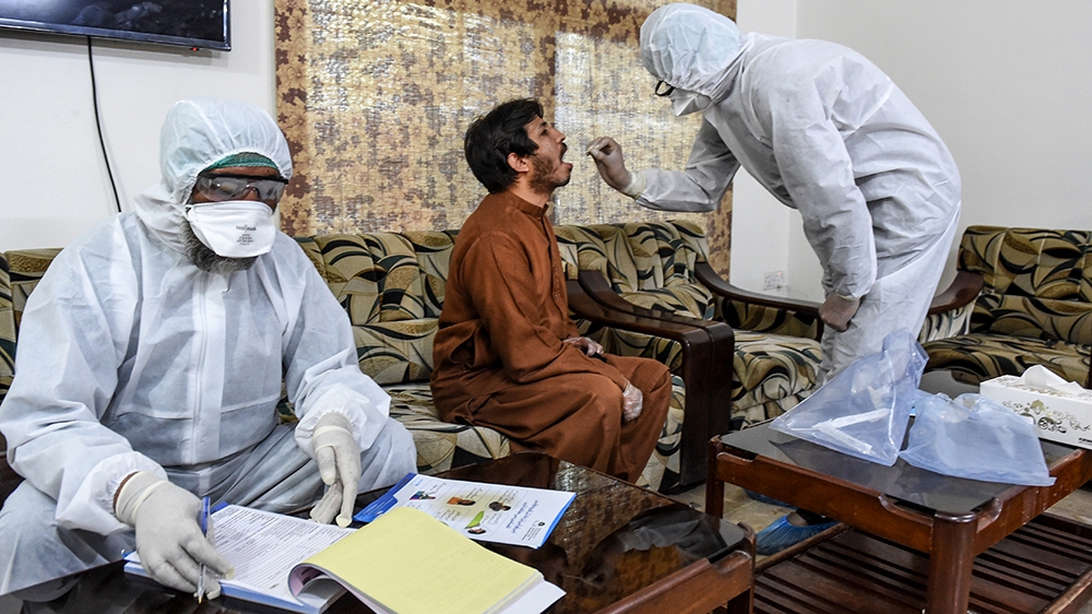 A health worker takes a COVID-19 sample from a journalist during a government-imposed nationwide lockdown in Quetta