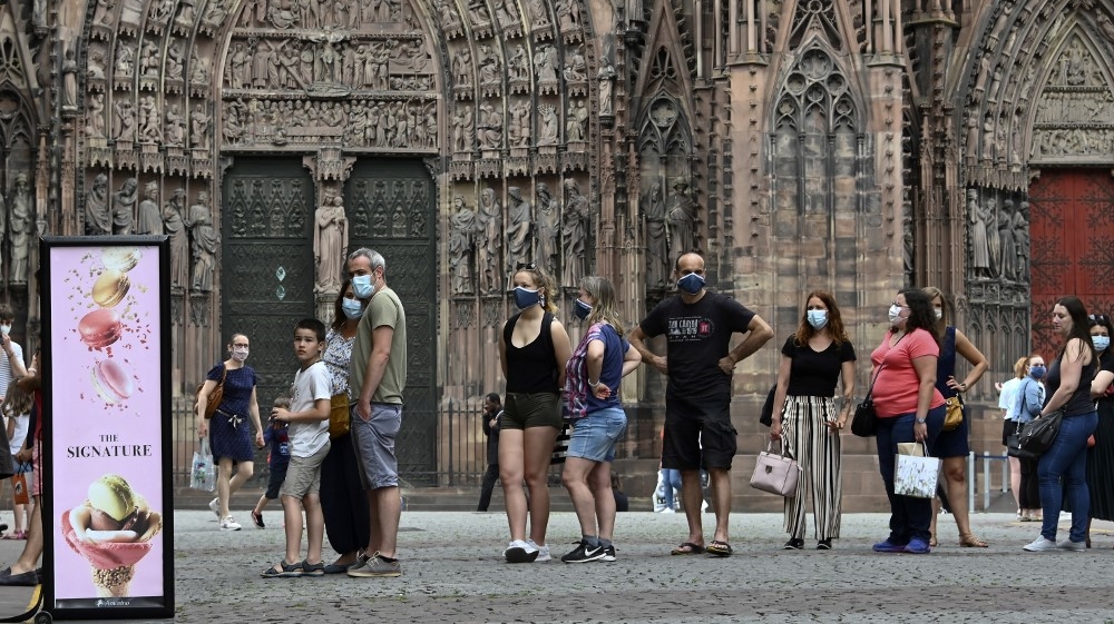 People wearing protective face masks while queueing at an ice cream shop on May 22, 2020, in Strasbourg, eastern France