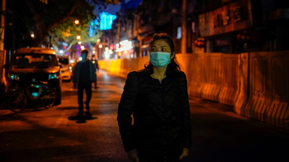 A woman wearing a mask walks along a street in Wuhan, China