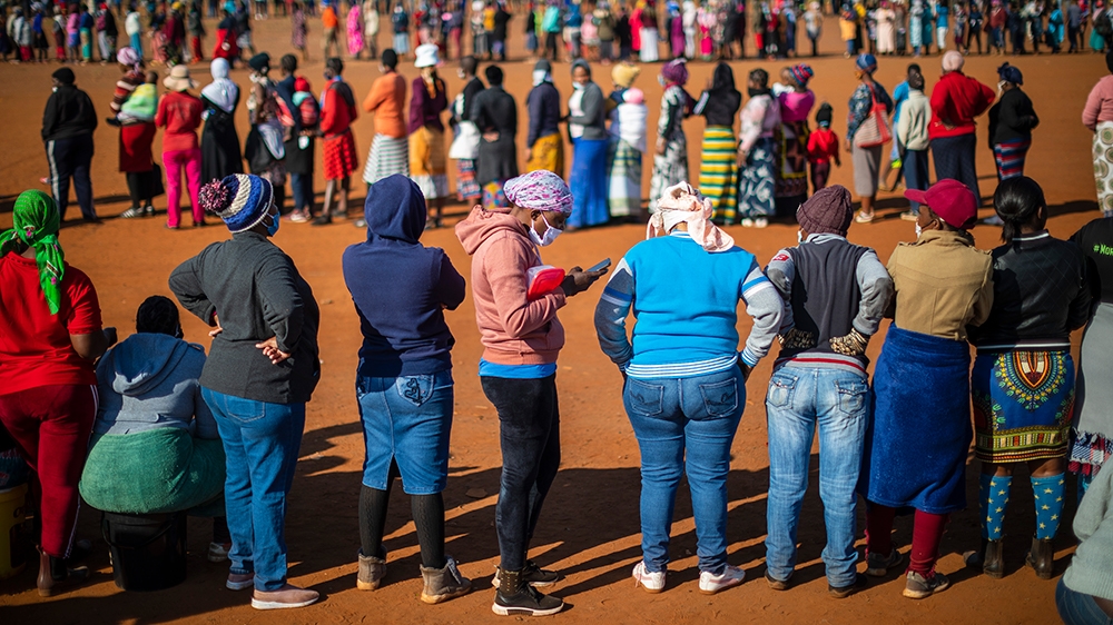People stand in a queue in at sunrise to wait for food being handed out during the national lockdown in Johannesburg, South Africa