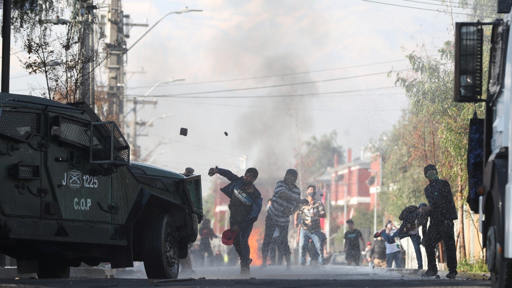 People clash with riot police while protesting against the lack of help from the government at ‘Cerrillos’ area in Santiago, Chile, on May 22, 2020