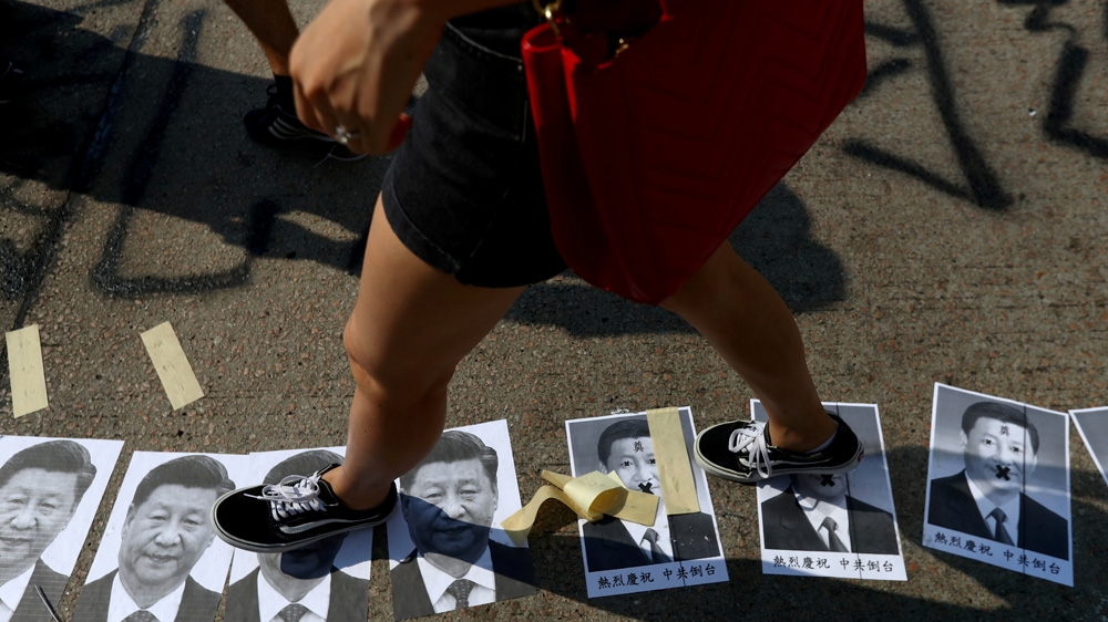 A protester walks across pictures of China’s President Xi Jinping during a demonstration in Hong Kong on October 1 2019, China’s National Day