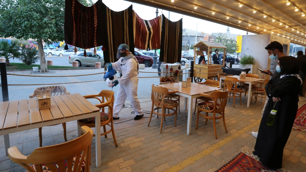 A worker wears a protective suit, following the outbreak of the coronavirus disease (COVID-19), sterilizes the tables before the customers sit down at a restaurant, in Riyadh