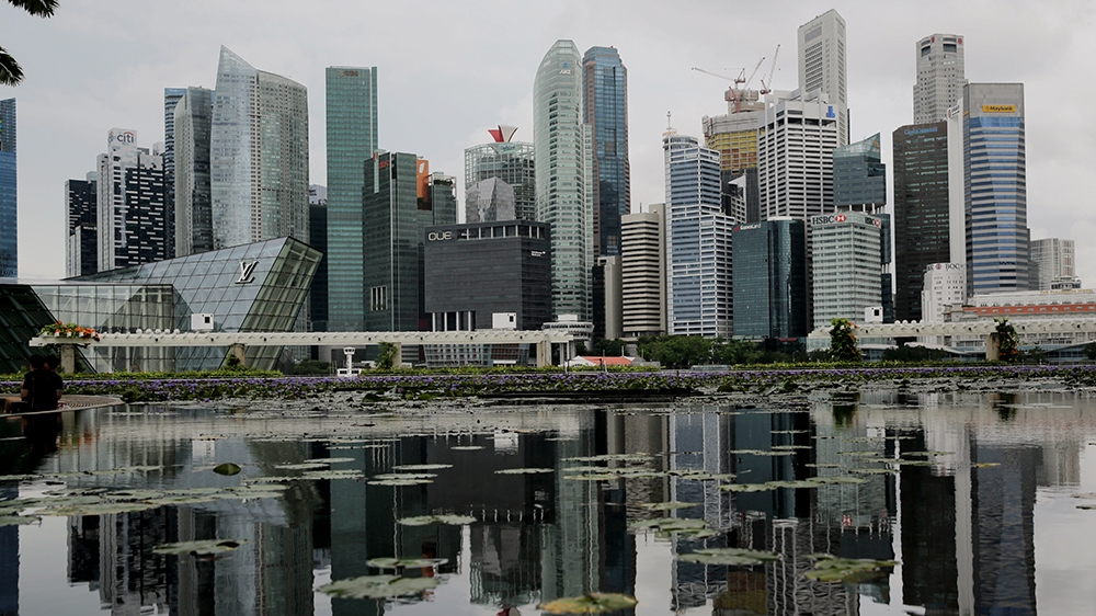epa08544543 The skyline of the financial district reflected in a lotus pond next to the ArtScience Museum in Singapore, 14 July 2020. Singapore's economy shrank a record 41.2 percent as a result of th