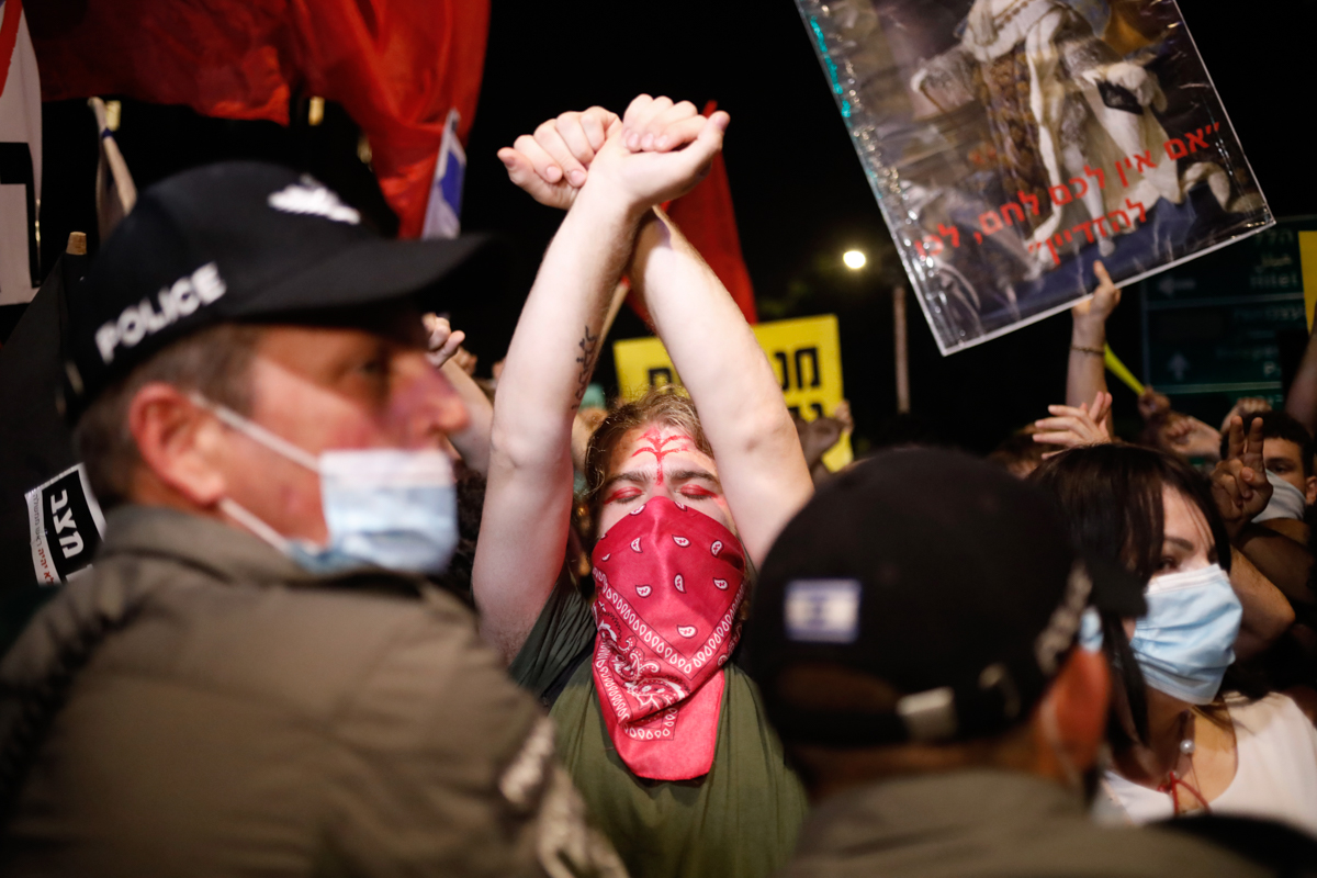 Demonstrators, defying orders to maintain social distancing requirements, chant slogans and blew horns outside Prime Minister''s residence in Jerusalem, Tuesday, July 14, 2020. Thousands of Israelis on