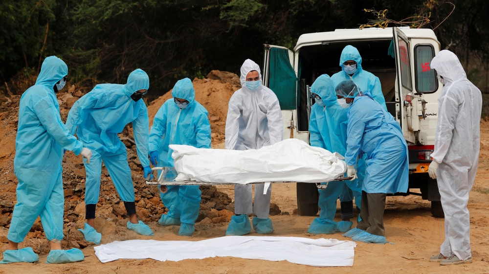 Relatives and health workers carry the body of a person who died from the coronavirus disease (COVID-19), before the burial at a graveyard in New Delhi, India, May 11, 2020. REUTERS/Adnan Abidi