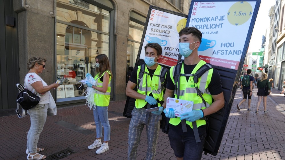 People wearing yellow vests hand out masks and information brochures where to wear the mandatory masks in the busiest streets of the city, during the coronavirus disease (COVID-19)