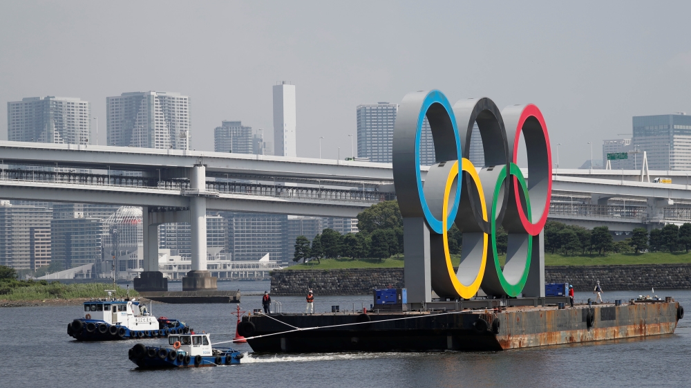Boats tow the giant Olympic rings, which are being temporarily removed for maintenance, at the waterfront area at Odaiba Marine Park in Tokyo