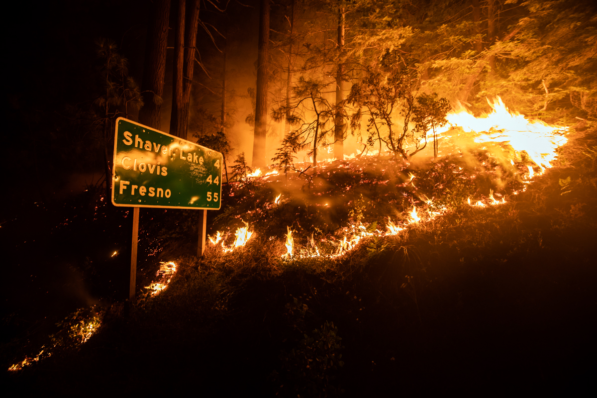 epa08652504 The Creek Fire burns next to a traffic sign giving the direction of Shaver Lake, Clovis and Fresno near Shaver Lake in the Sierra National Forest, California, USA, 07 September 2020. Accor