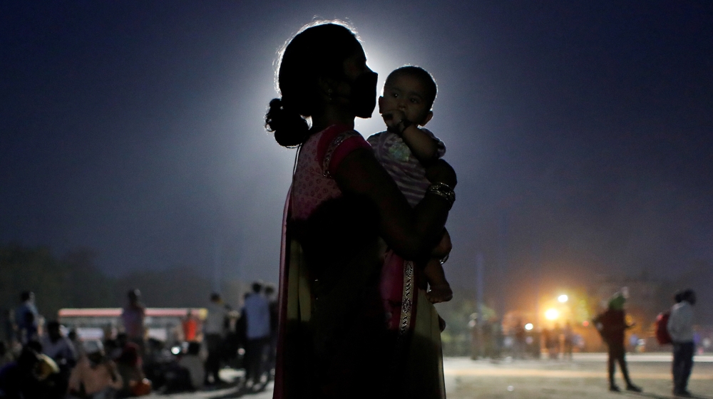 A woman and her baby wait for a bus to take them to a railway station to board a train to their home state of Uttar Pradesh, after a limited reopening of India''s giant rail network following a nearly