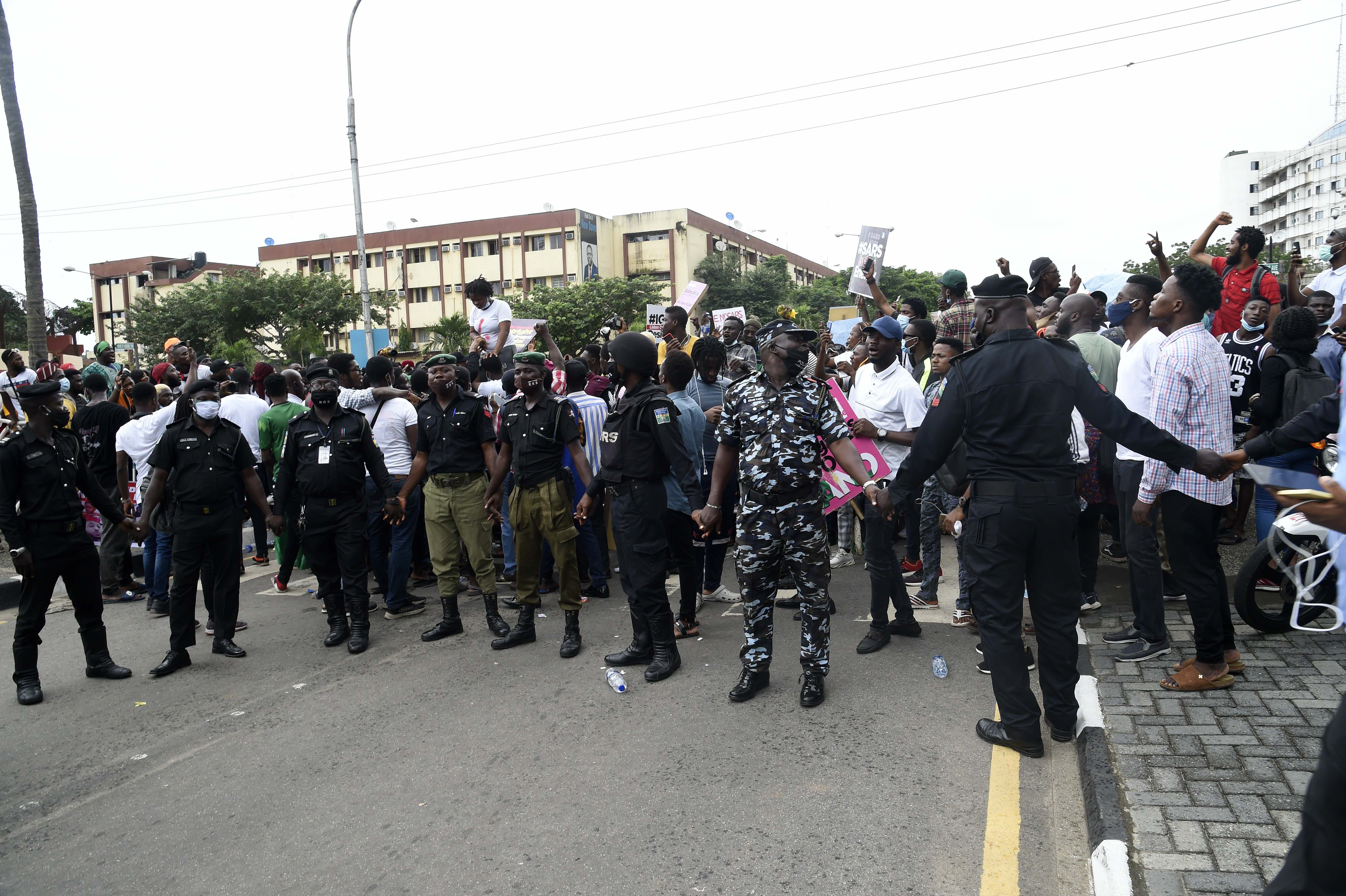 Policemen hold hands to barricade protesters to prevent people gaining entry at a government house during the continuing demonstrations to call for the scrapping of the controversial police unit at Ikeja