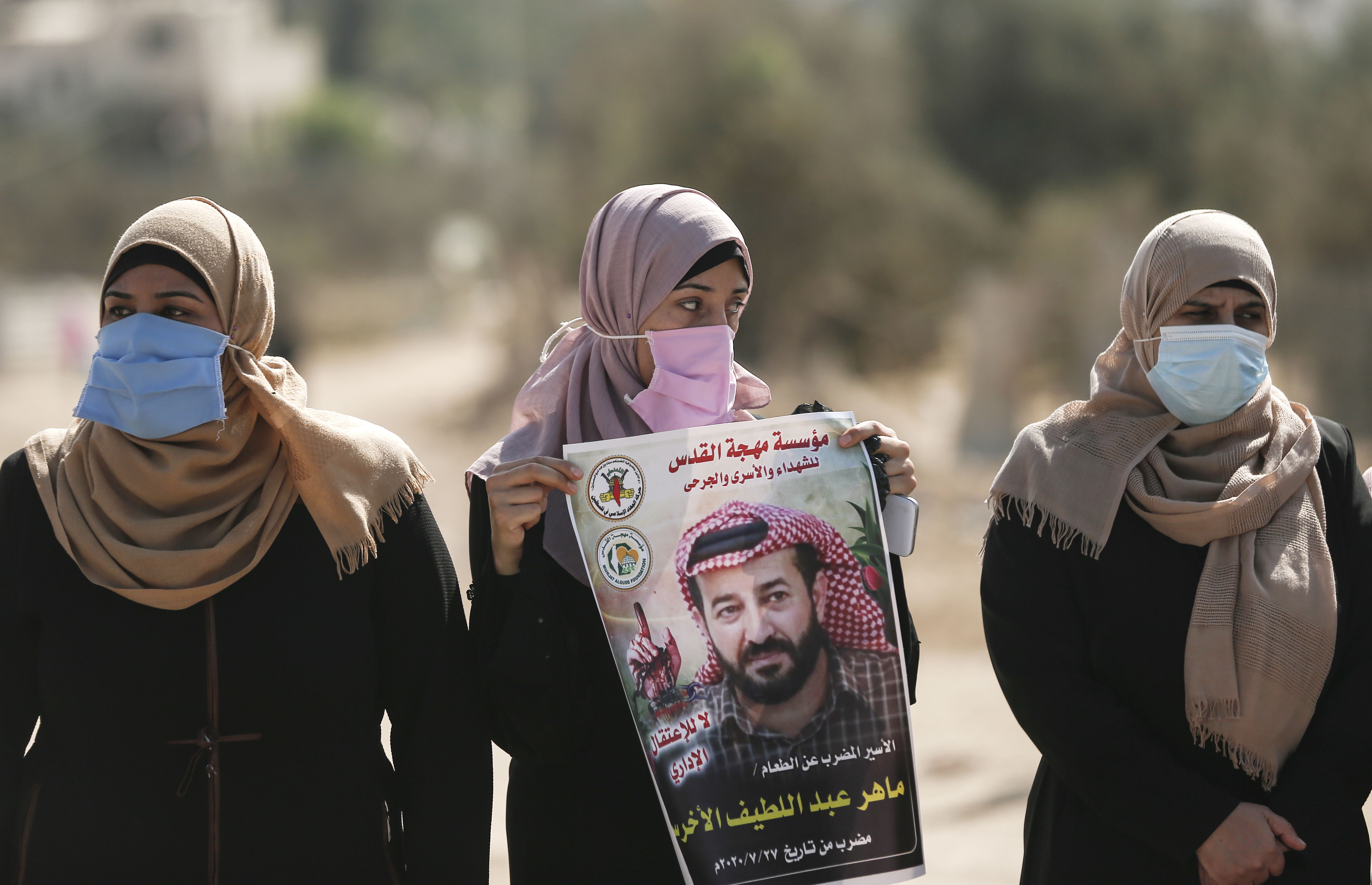 Palestinian women hold a placard bearing the portrait of Maher al-Akhras during a demonstration demanding his release at Beit Hanoon, known as Erez to Israelis, in Gaza Strip