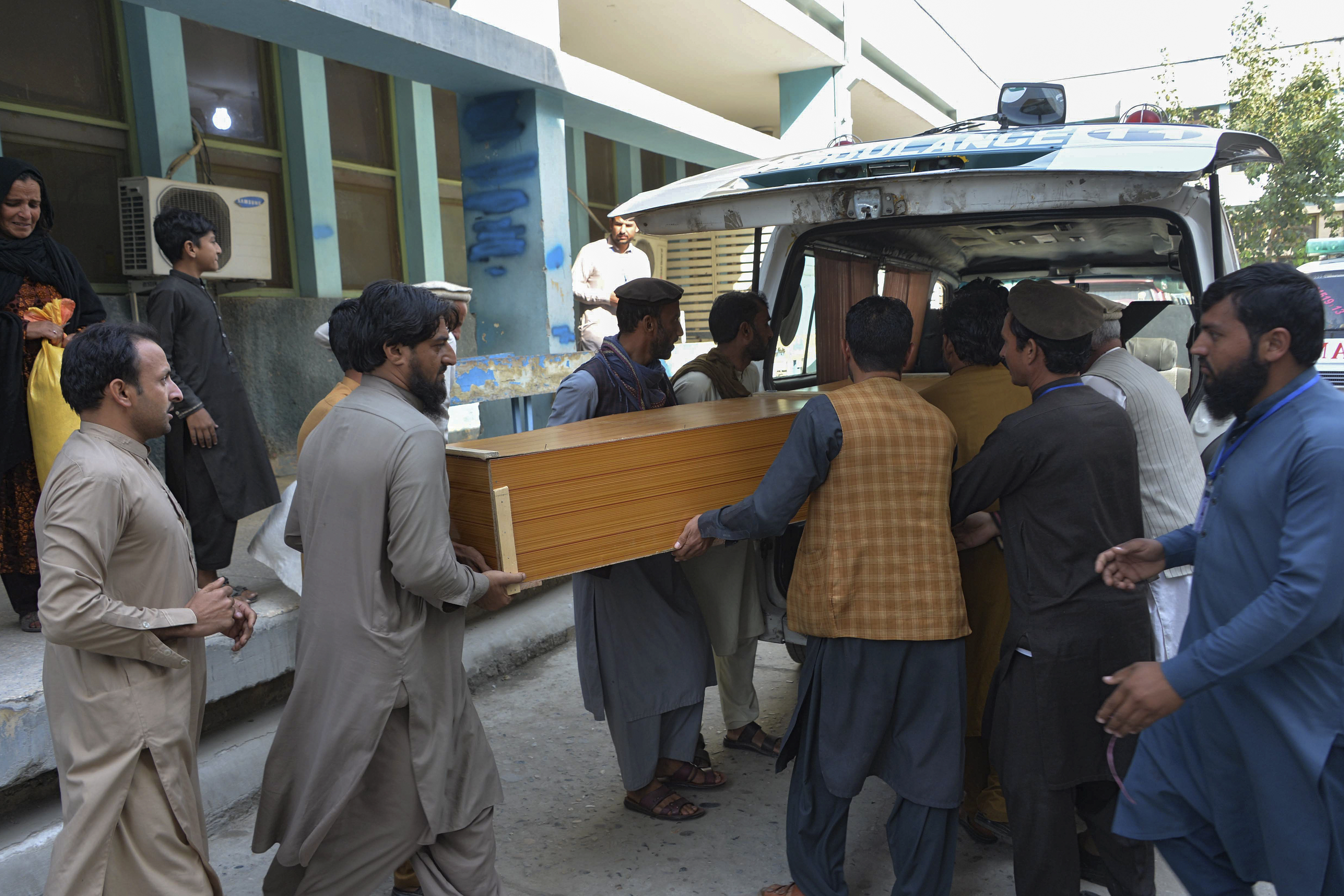 Relatives carry the coffin of a victim killed in the stampede, outside a mortuary in Jalalabad