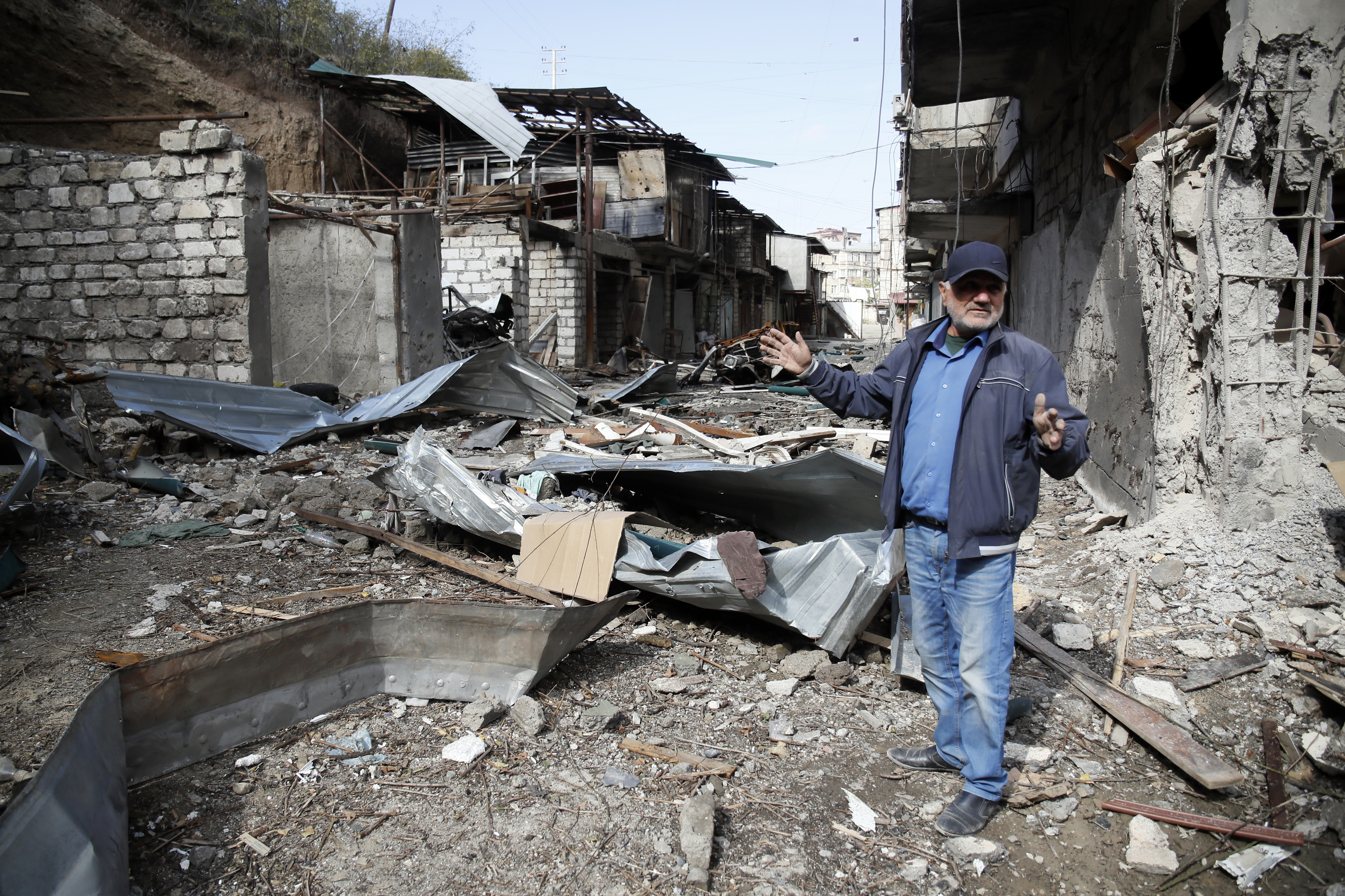 Eduard Chechyan gestures in the yard of his apartment building destroyed by shelling in Nagorno-Karabakh region [AP Photo]