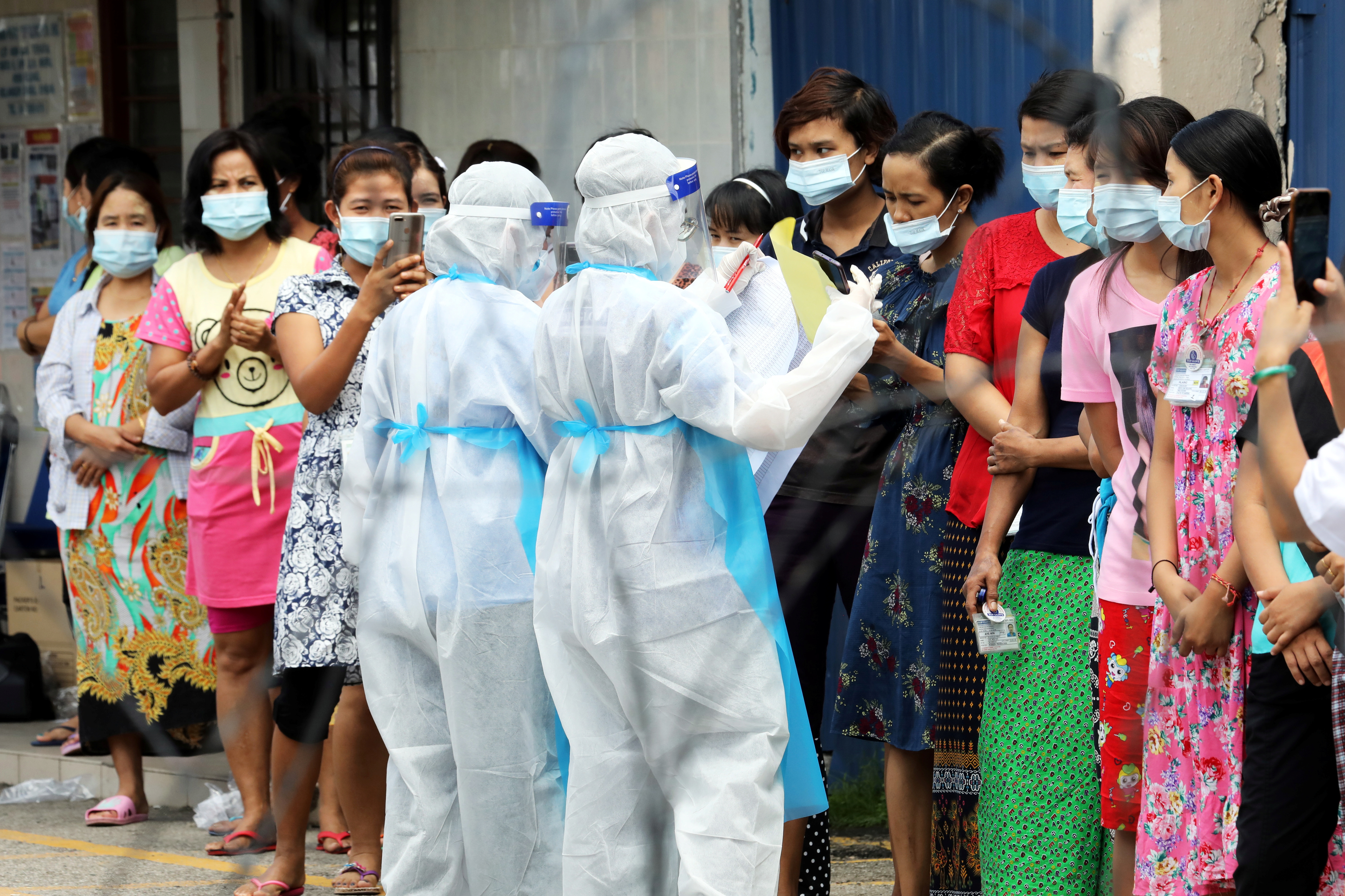 Top Glove workers wait in line to be tested for the coronavirus disease (COVID-19) outside a hostel under enhanced lockdown in Malaysia