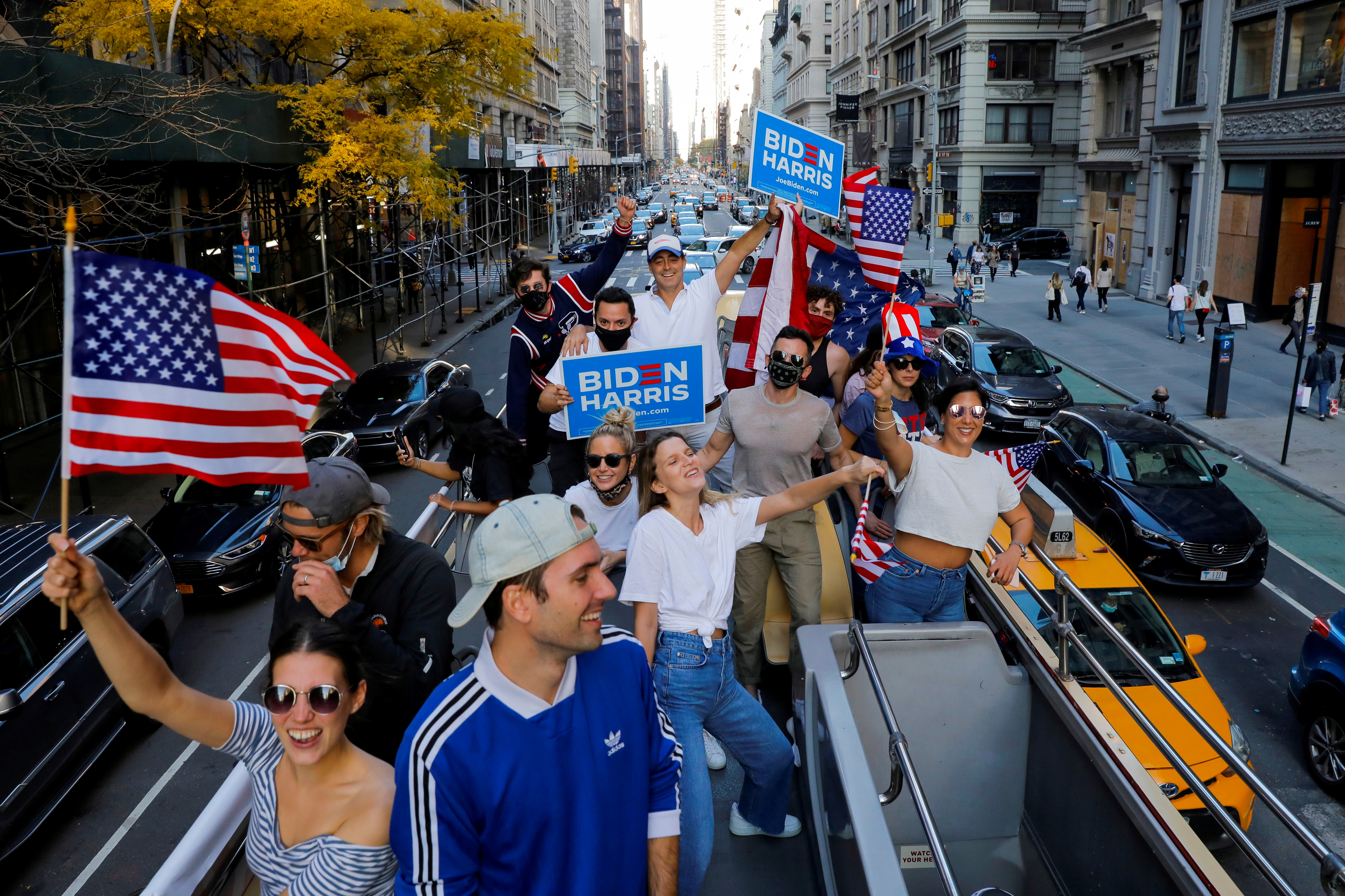 A group of New Yorkers celebrate Joe Biden's election victory on an open top double decker bus in Manhattan, New York City, US, November 8, 2020. [Andrew Kelly/Reuters]