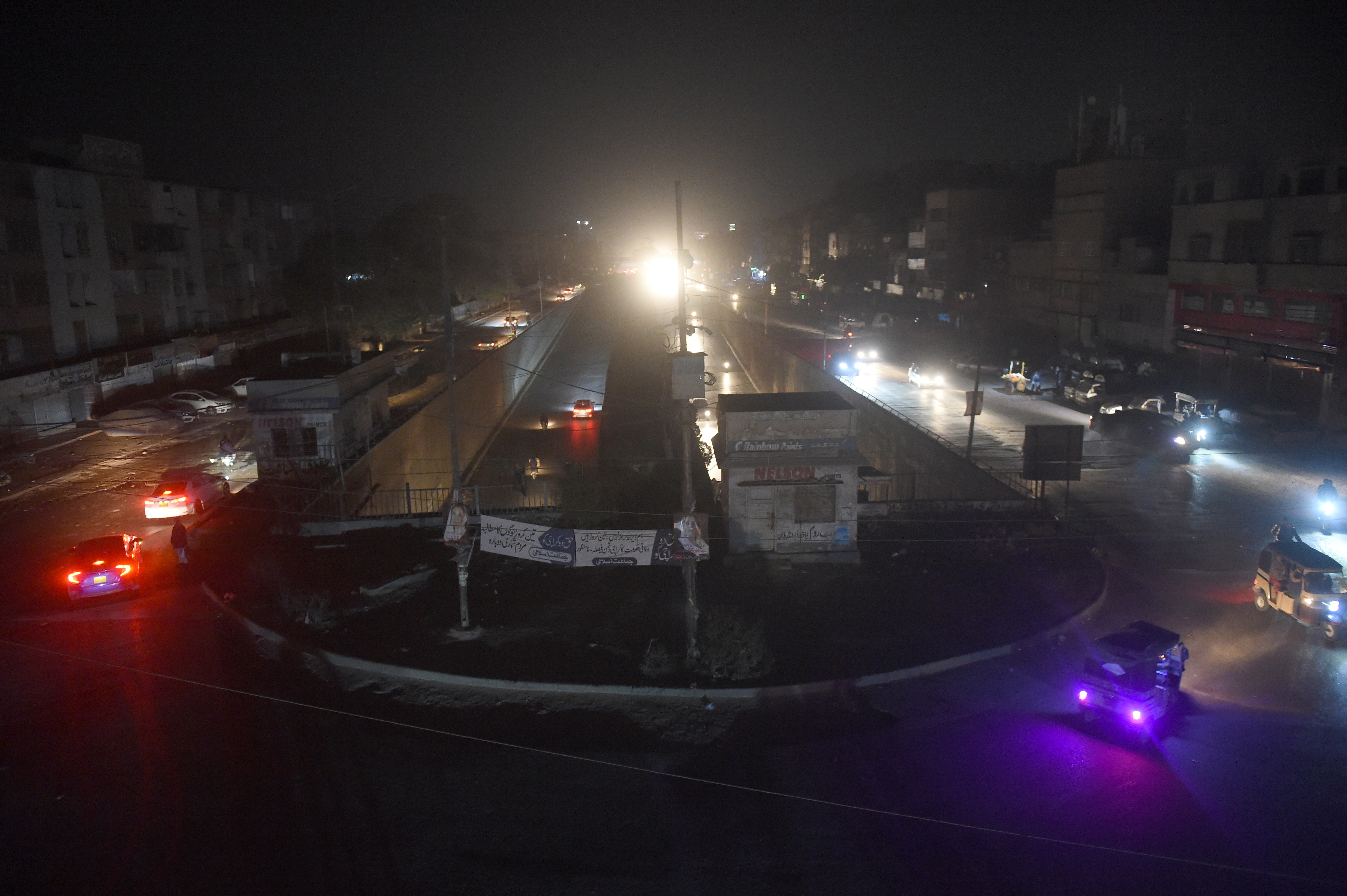 Motorists drive through a residential area during a power blackout in Pakistan’s port city of Karachi early on Sunday