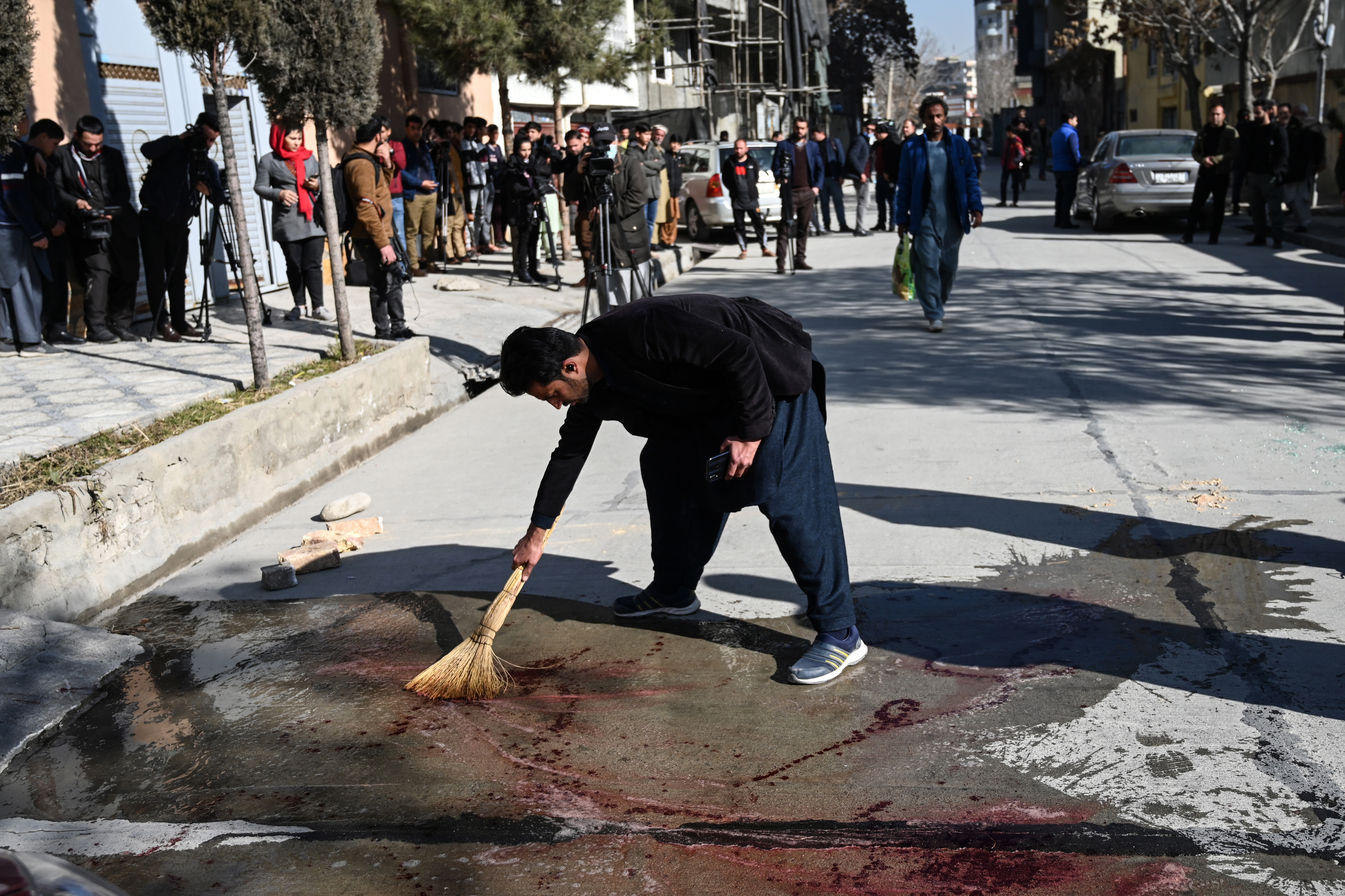 A resident washes a road after attackers shot dead two Afghan female judges on Sunday