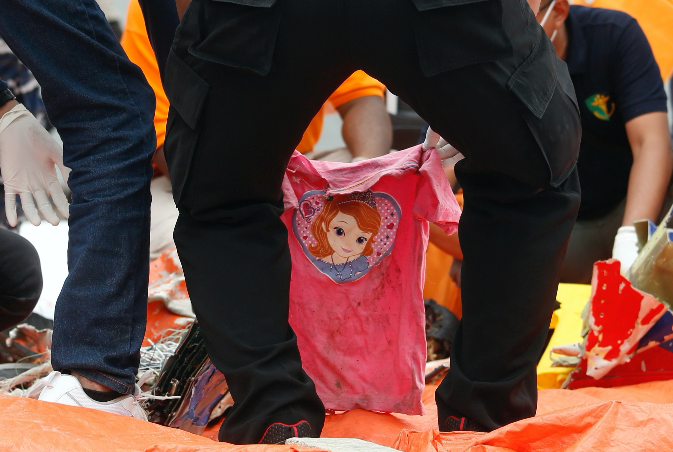 Indonesian rescue members handle a pink T-shirt during the recovery of the crashed Sriwijaya Air plane