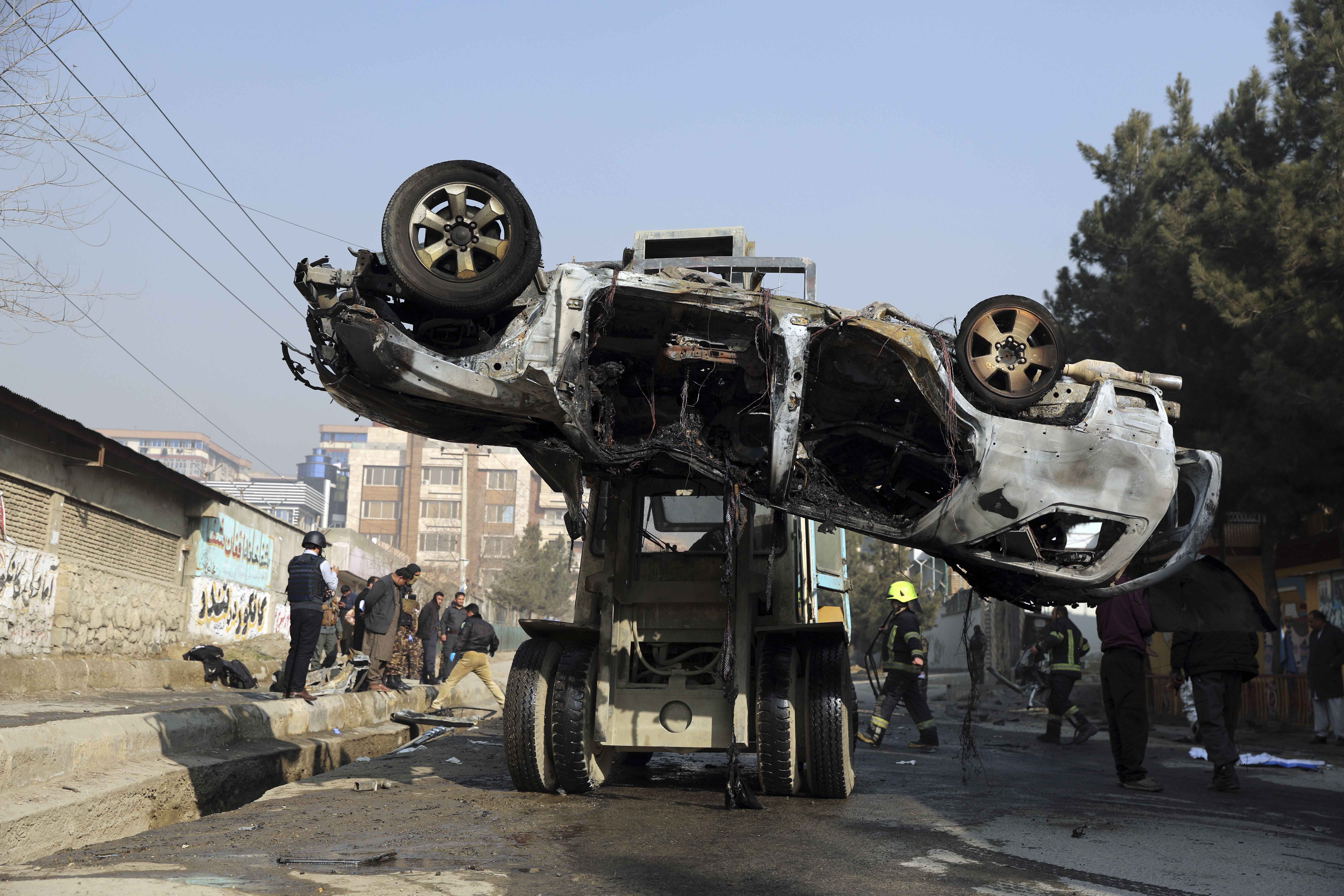 Afghan security personnel remove a damaged vehicle after a bomb attack in Kabul, Afghanistan