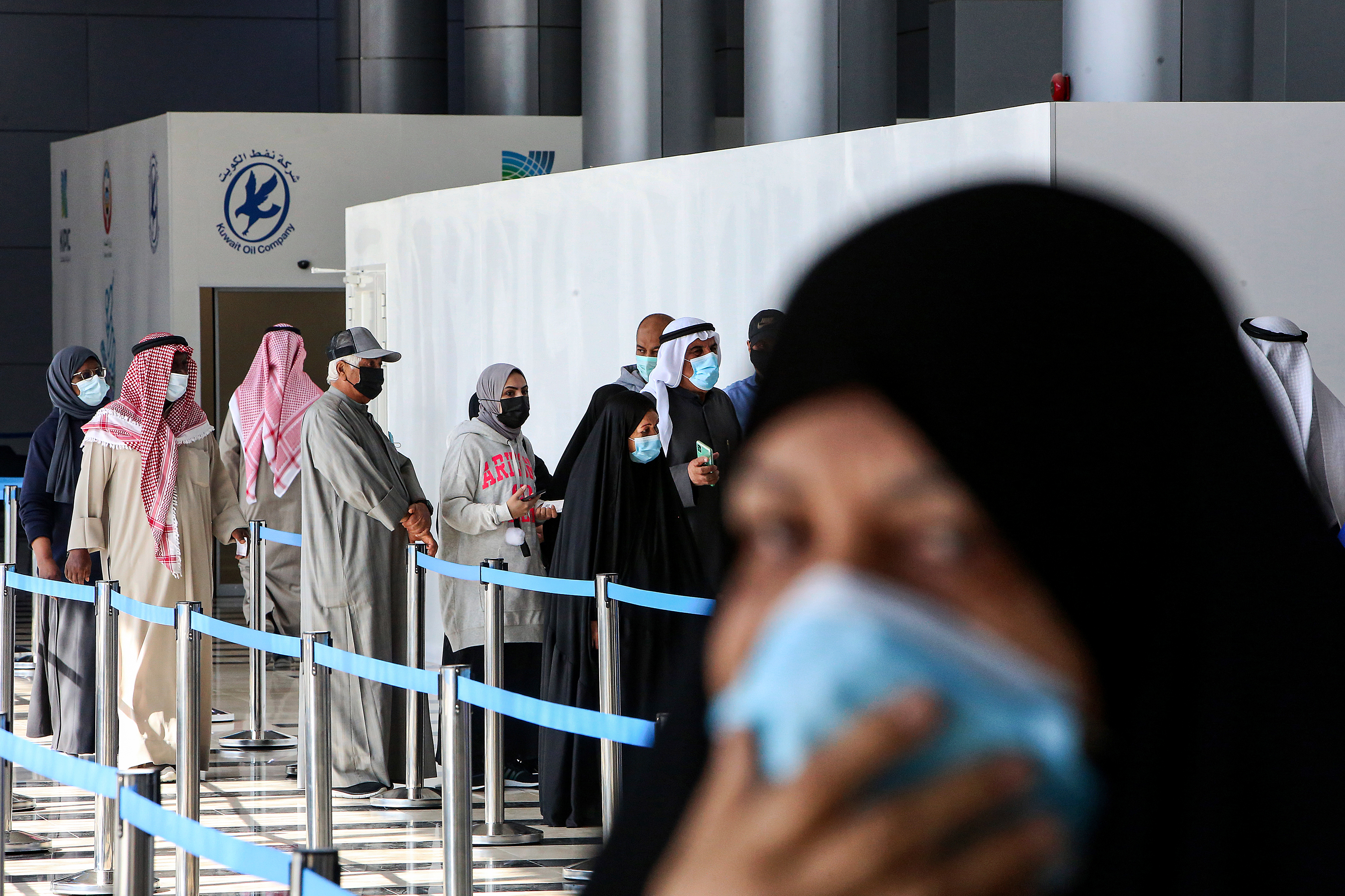 People queue to receive a dose of COVID-19 vaccine at the make-shift vaccination centre at the Kuwait International Fairground, in the Mishref suburb south of Kuwait City