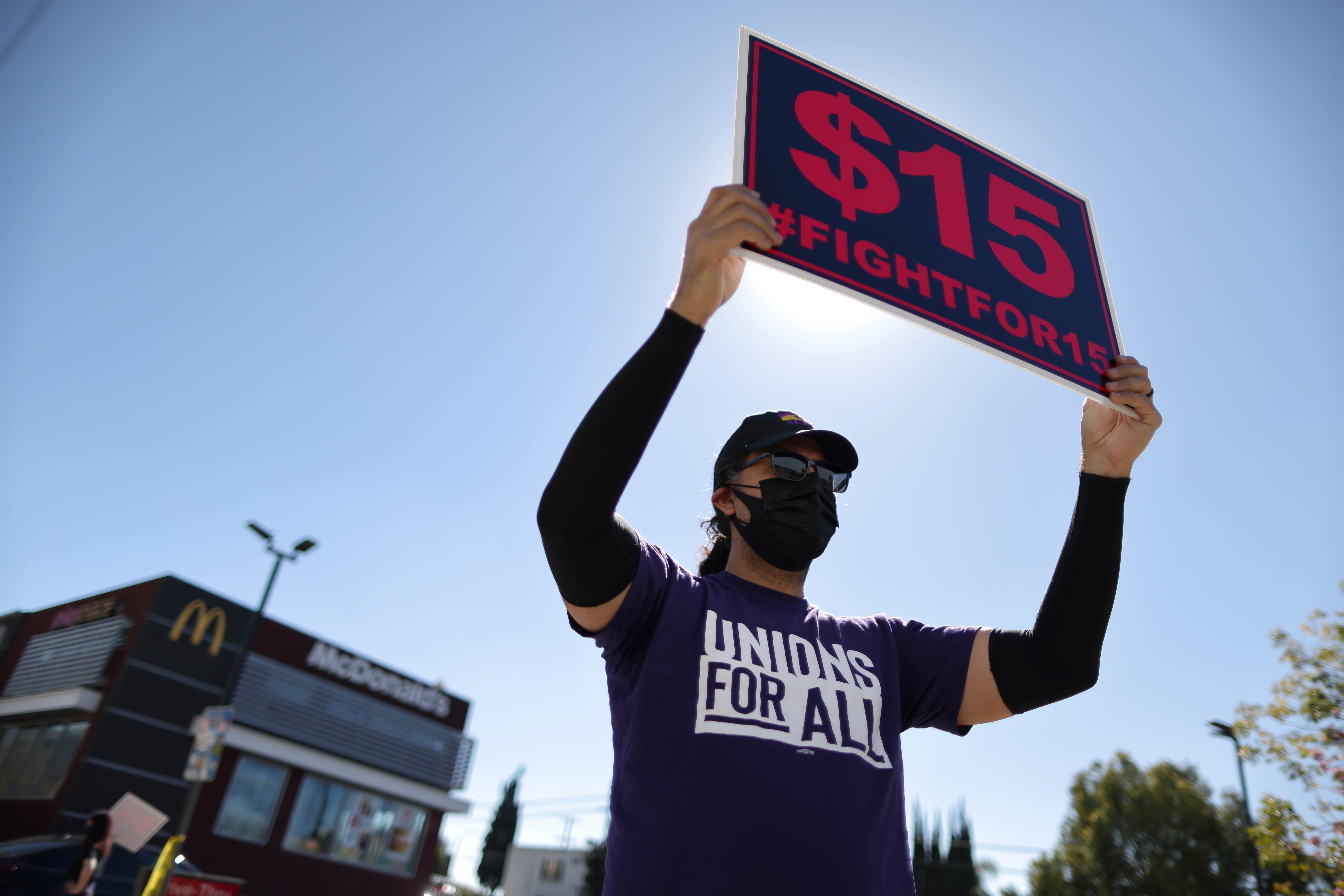A man holds up a minimum wage sign at a rally held by fast-food workers and supporters in Los Angeles, California, the United States