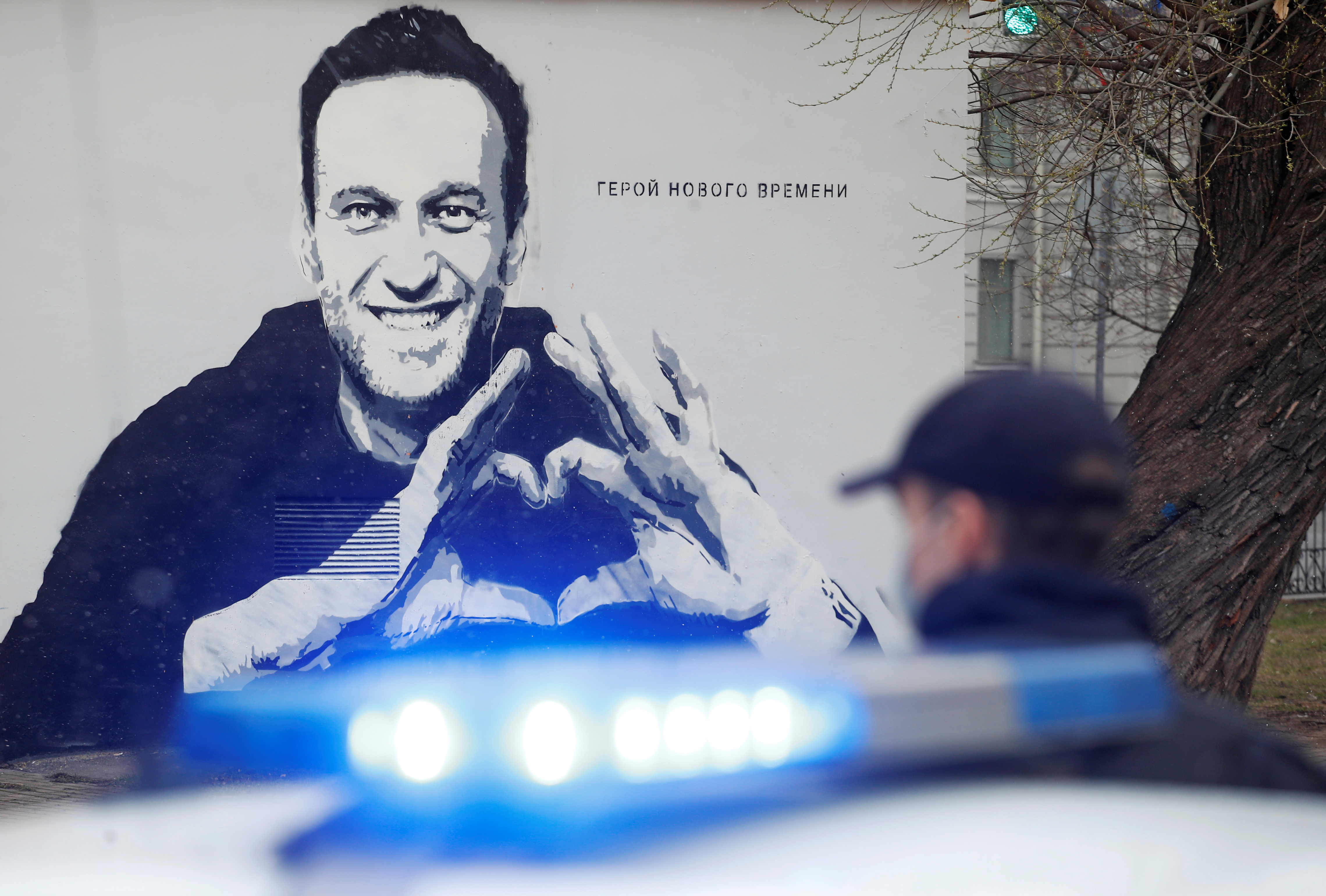 A police officer stands next to a car in front of a graffiti depicting jailed Russian opposition politician Alexei Navalny in Saint Petersburg, Russia April 28, 2021.