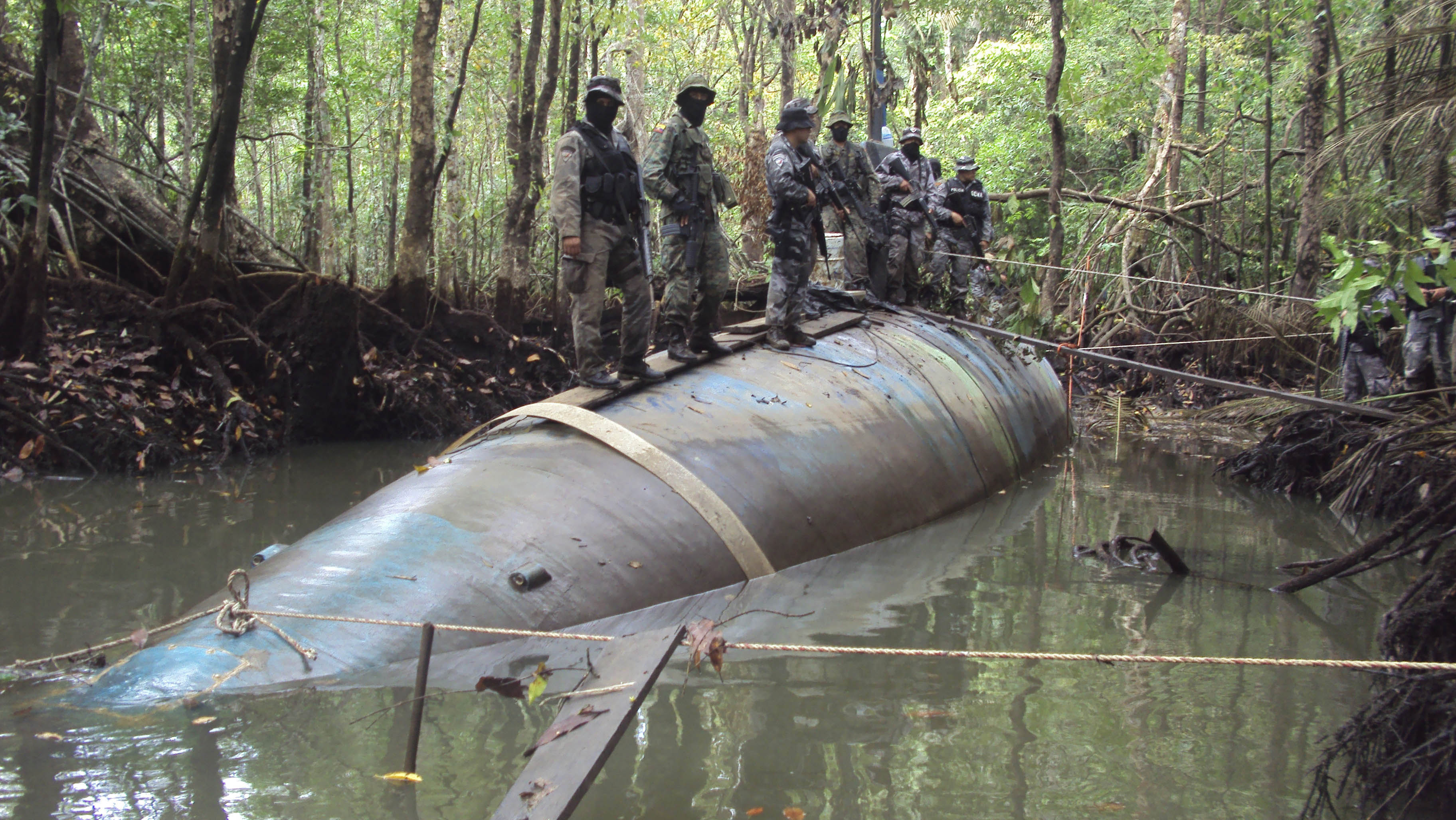 Soldiers stand on a seized submarine in the jungle region of La Loma in Ecuador on July 3, 2010. DEA officials said that the diesel electric-powered submarine was constructed in a remote jungle and captured near a tributary close to the Ecuador-Colombia border and is capable of transporting tonnes of cocaine. Ecuadorean authorities seized the sub before it could make its maiden voyage [AP Photo]