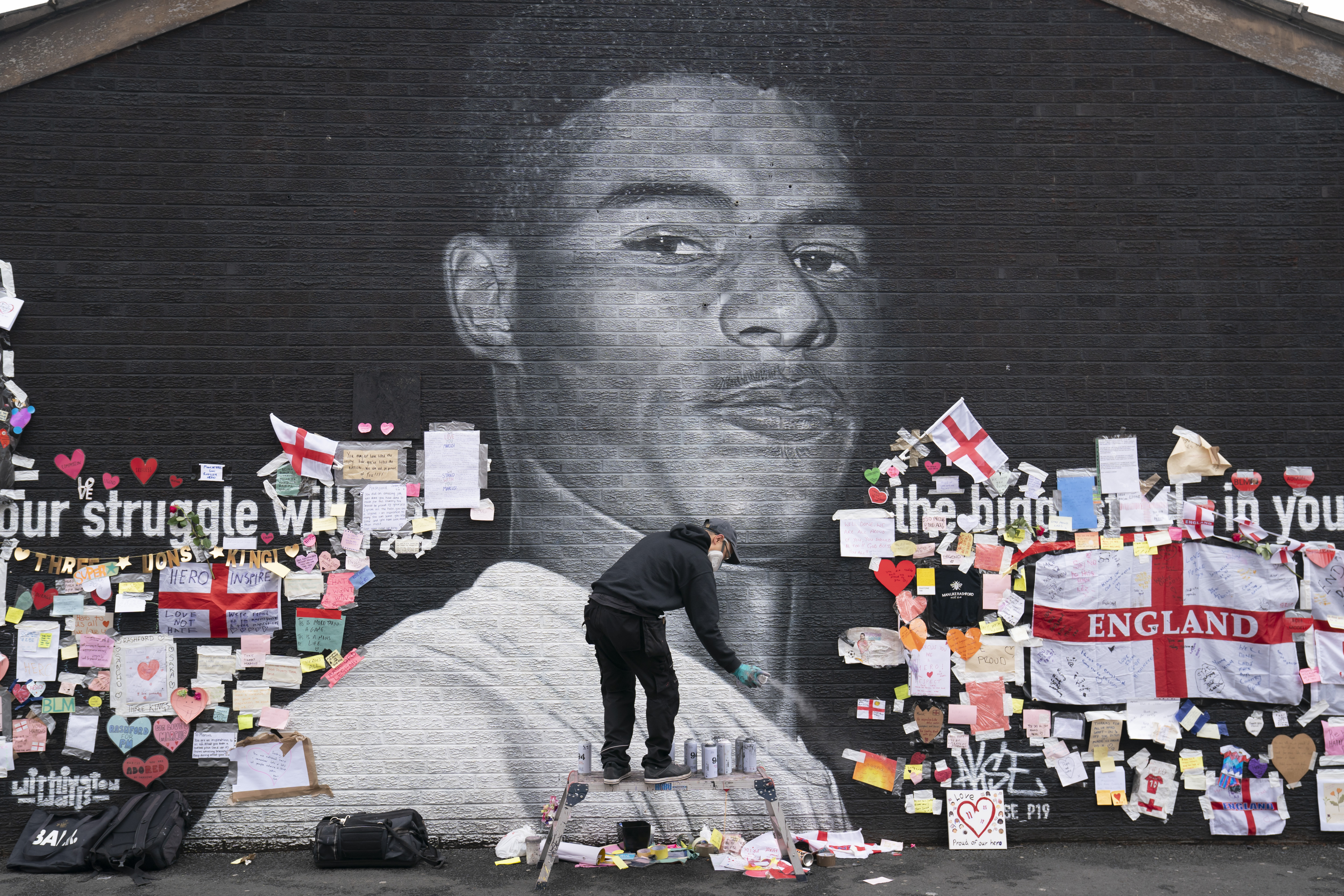 Street artist Akse P19 repairs the mural of Manchester United striker and England player Marcus Rashford on the wall of the Coffee House Cafe on Copson Street, in Withington, Manchester