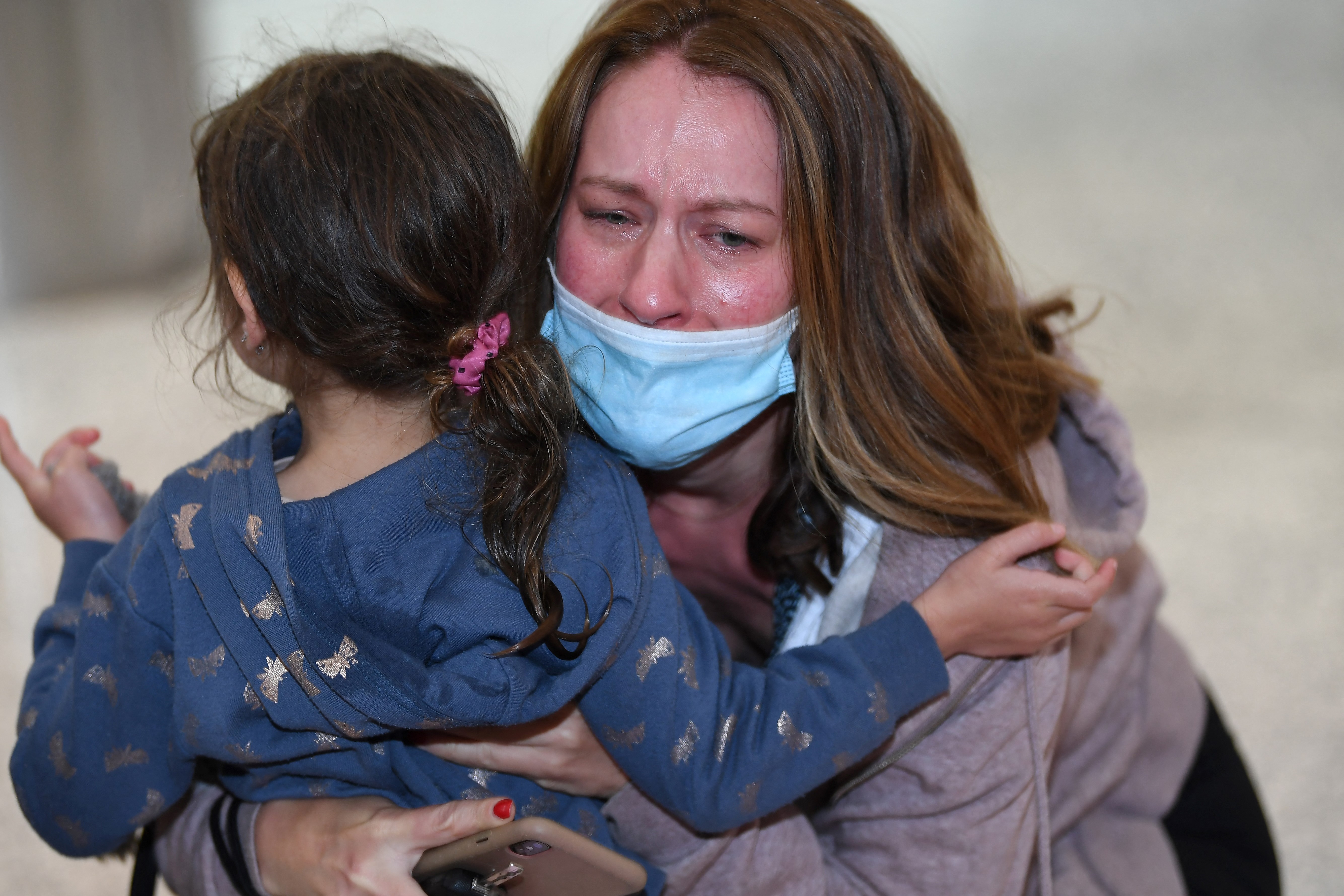 Family members embrace upon being reunited on arrival at Sydney’s international airport on November 1, 2021