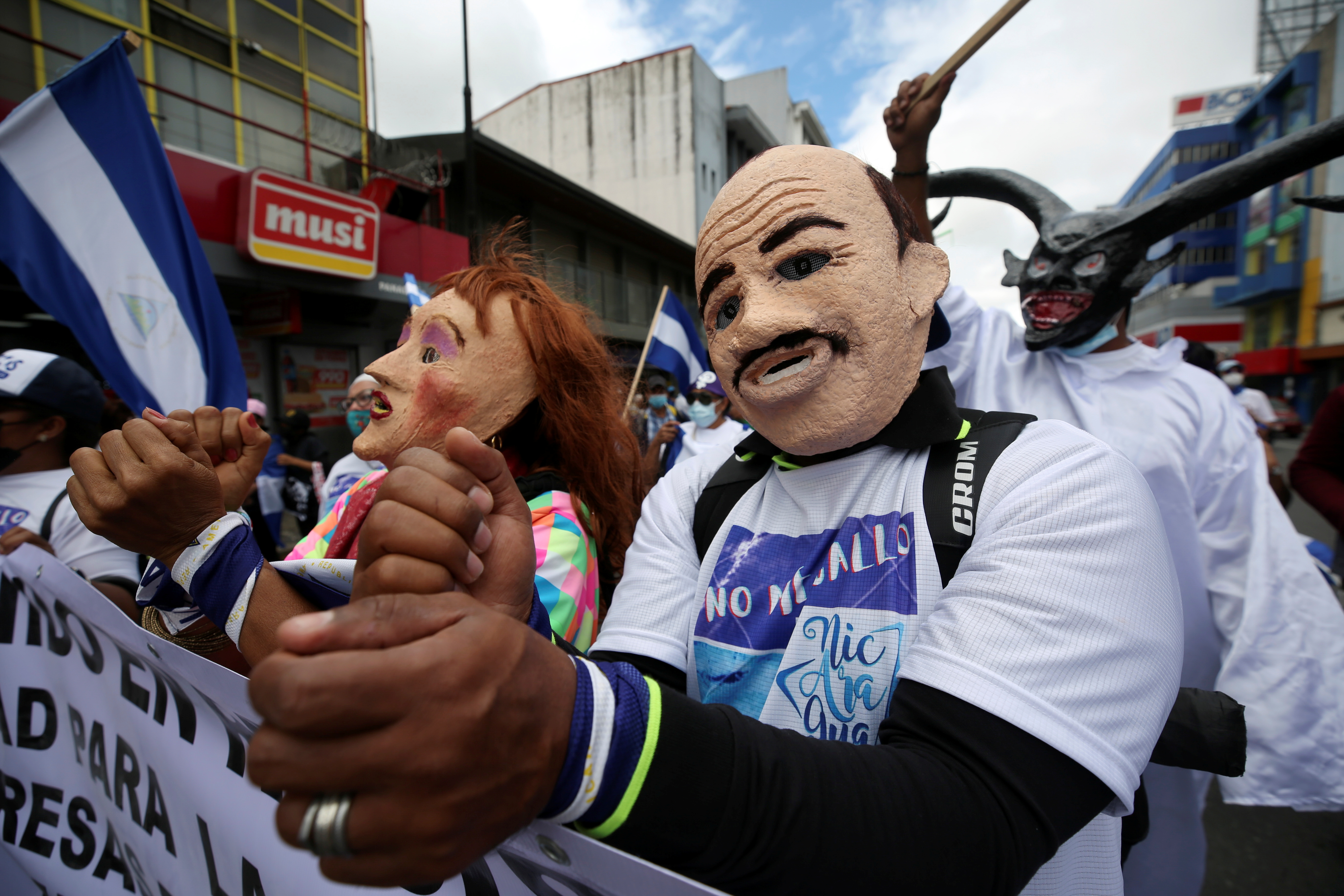 Demonstrators wearing masks to mock Nicaraguan President Daniel Ortega and his wife Vice President Rosario Murillo, take part in a march of Nicaraguans exiled in Costa Rica to protest against the presidential election in Nicaragua, in San Jose, Costa Rica, November 7, 2021