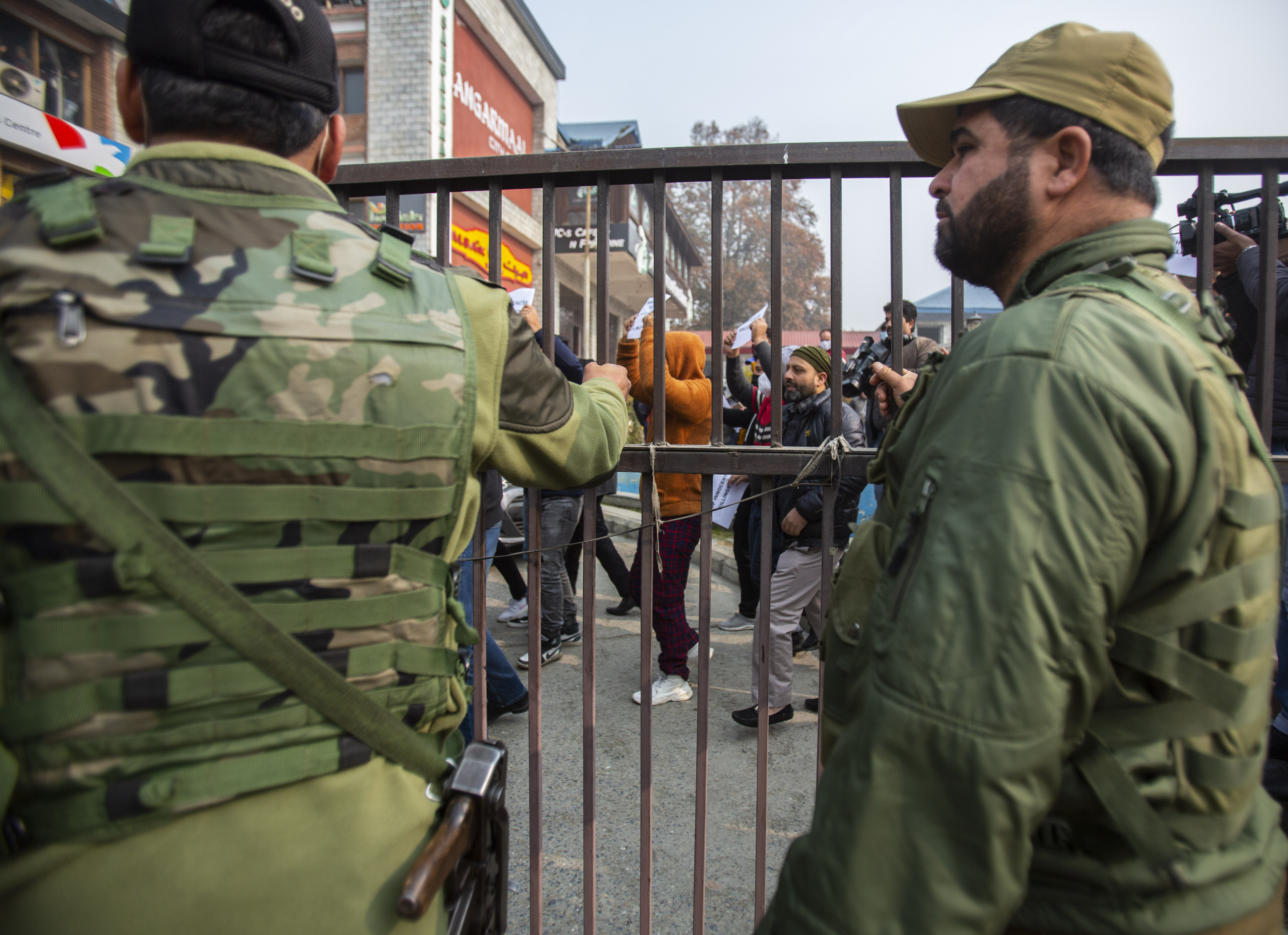Policemen watch Kashmiris participate in a protest in Srinagar