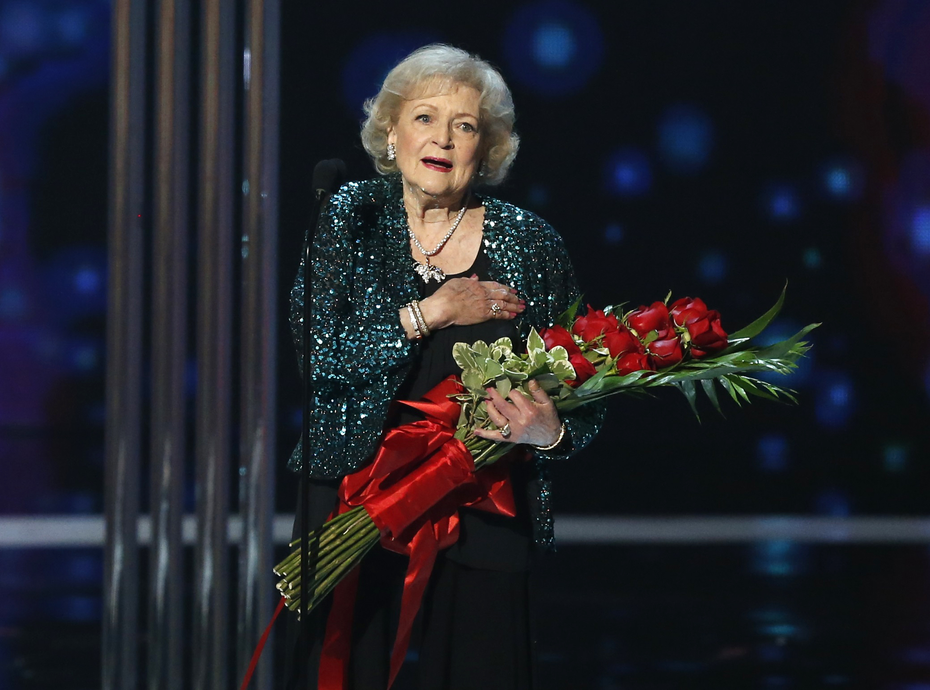 Actress Betty White holds flowers while standing on stage at the People's Choice awards