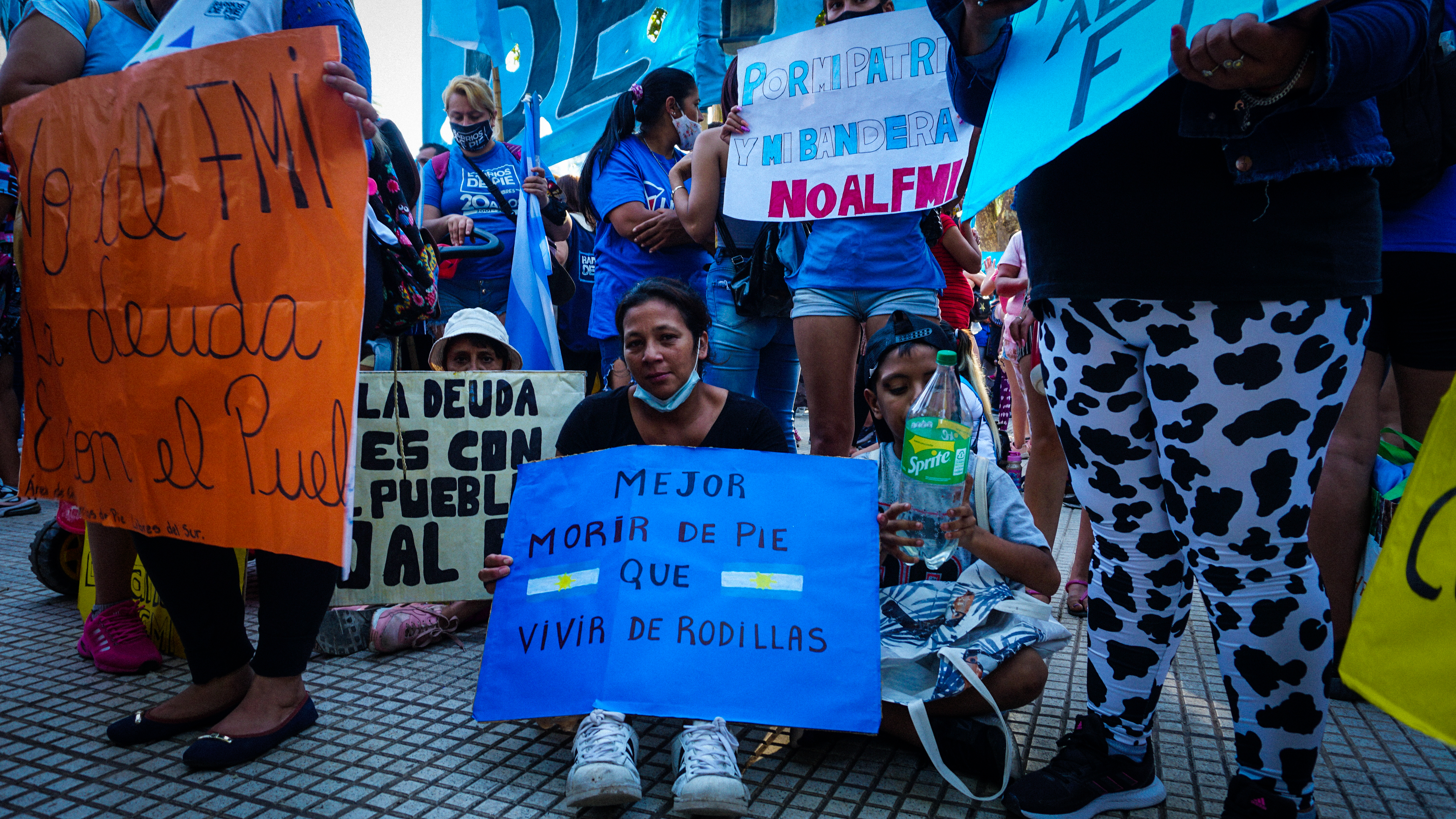 A woman holds a sign that says, ‘It’s better to live on your feet than die on your knees at a march in Buenos Aires, Argentina